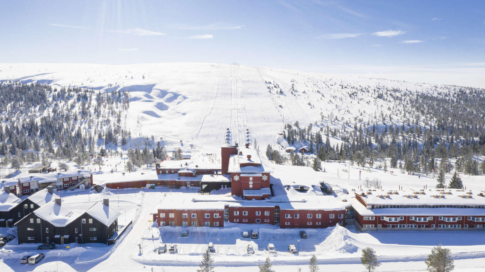 Vinterlandskap i fjällen med skidbackar och snötäckta byggnader under klarblå himmel