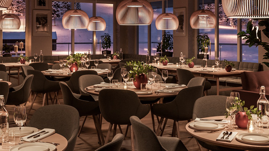 Elegant restauranginteriör med uppsatt bord, moderna lampor och panoramautsikt under solnedgång