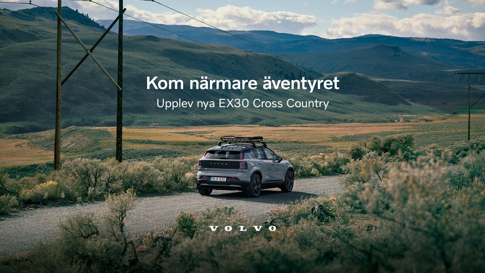 Volvo EX30 Cross Country kör på grusväg i naturskönt landskap med berg och blå himmel