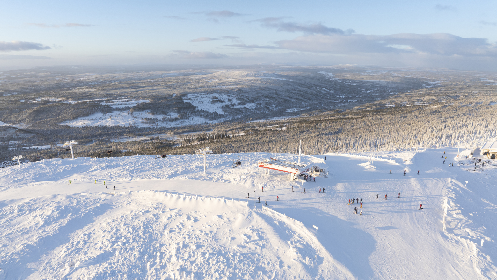 Winter landscape with snow-covered mountains and skiers in Sälen, Sweden, under a clear sky