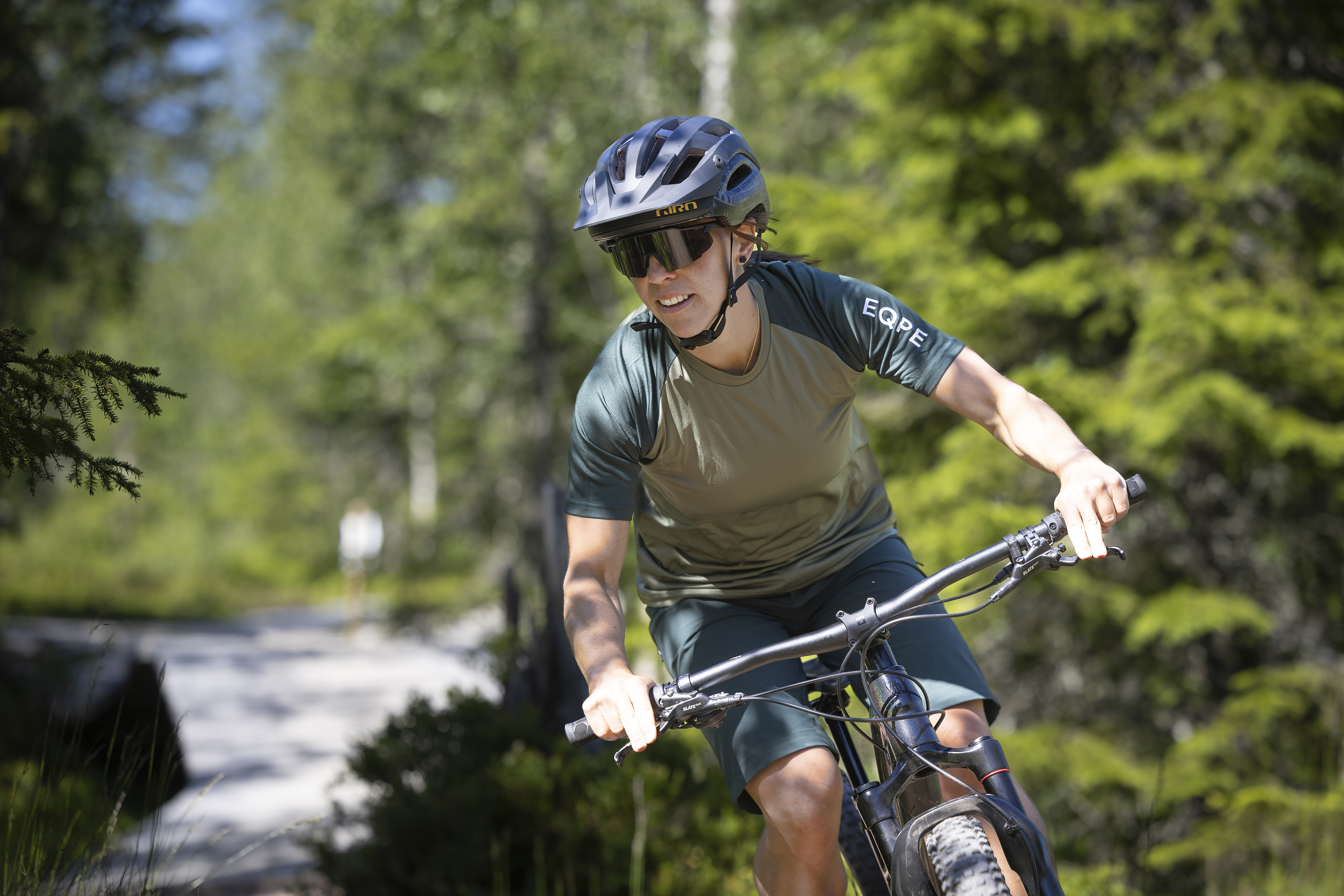 Person cyklar mountainbike på stig i grönskande skog