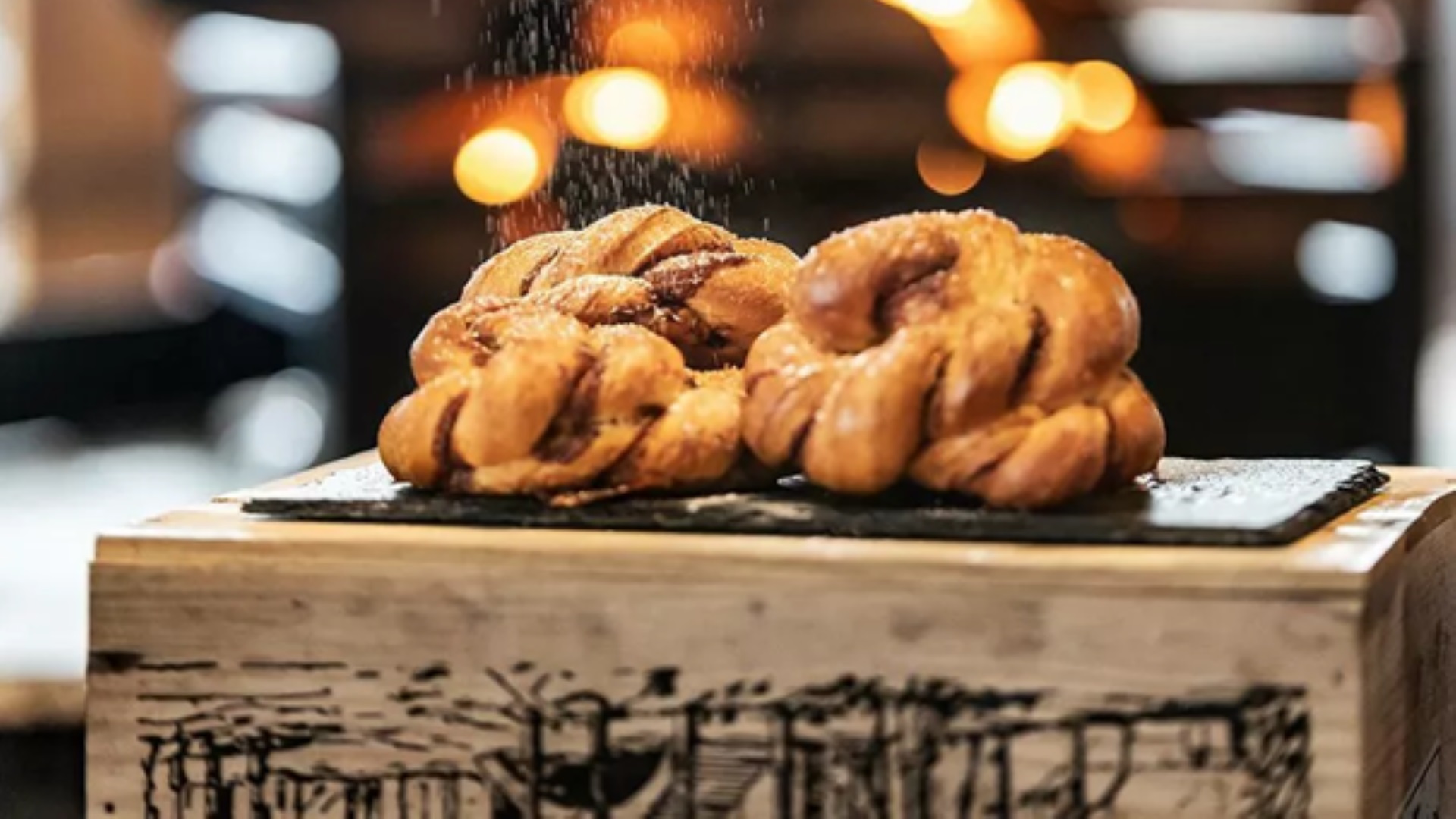 Kanelbullar strödda med socker på ett träbord framför en öppen eld
