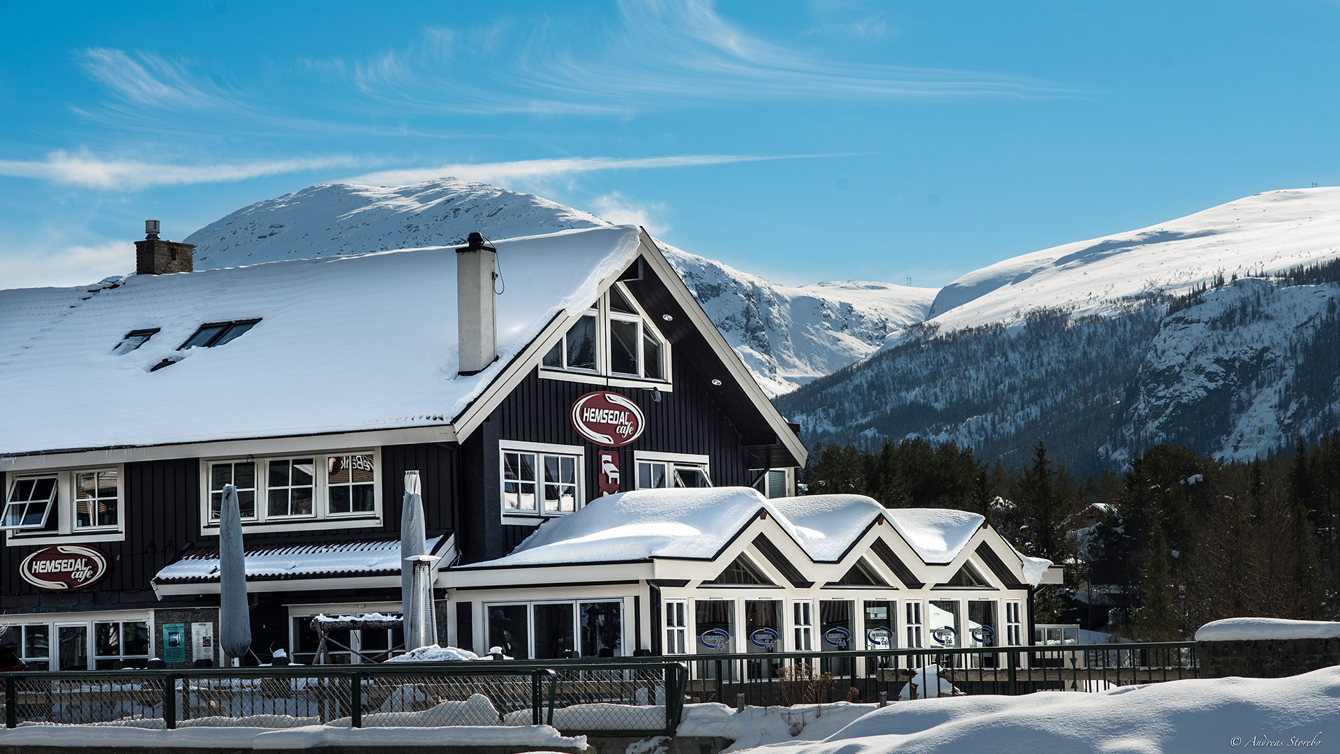 Snötäckt fjällstuga i Hemsedal med berg i bakgrunden under klarblå himmel