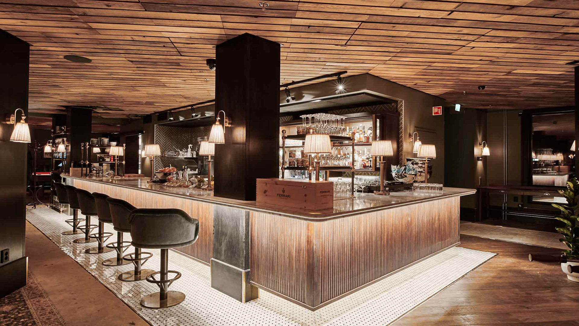Interiör av en modern, elegant bar med träpaneltak, bekväma stolar, och upplyst bardisk