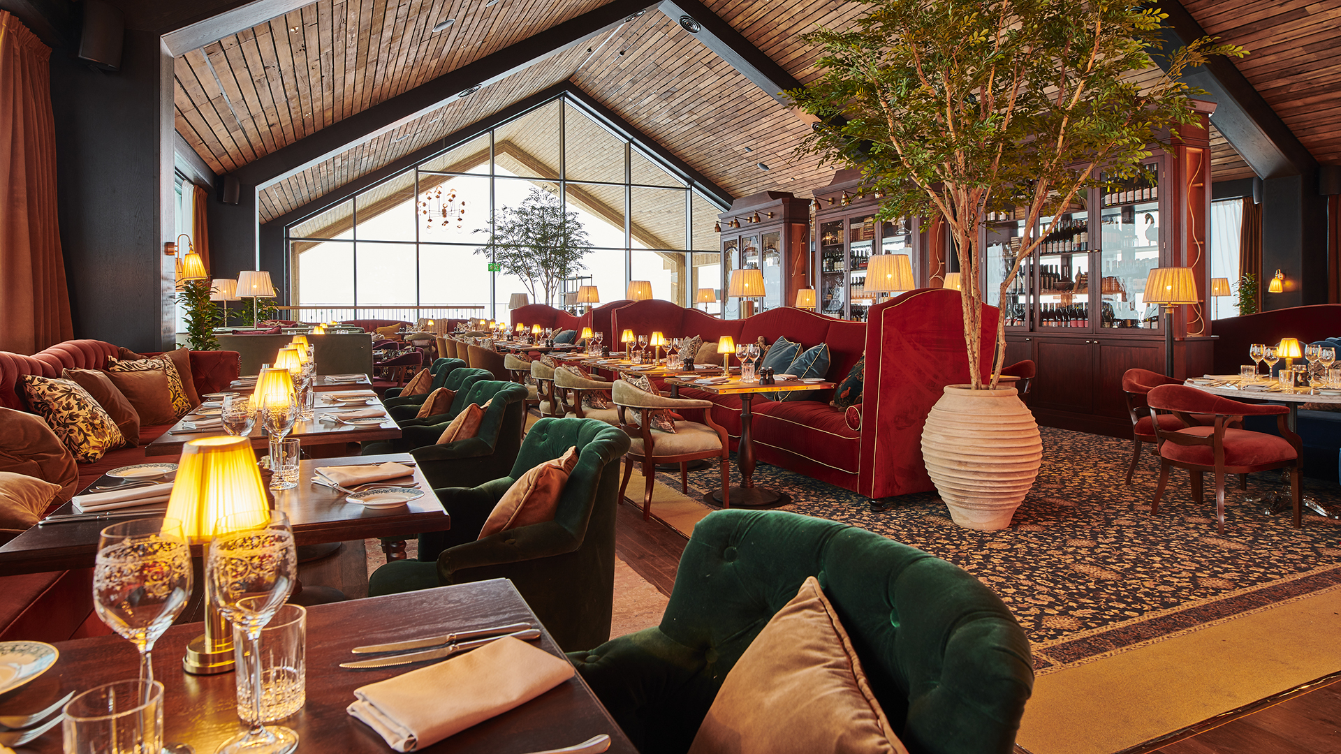 Elegant restauranginteriör med mysig belysning, bekväma stolar och stora fönster, vilket skapar en inbjudande atmosfär för middagsgäster