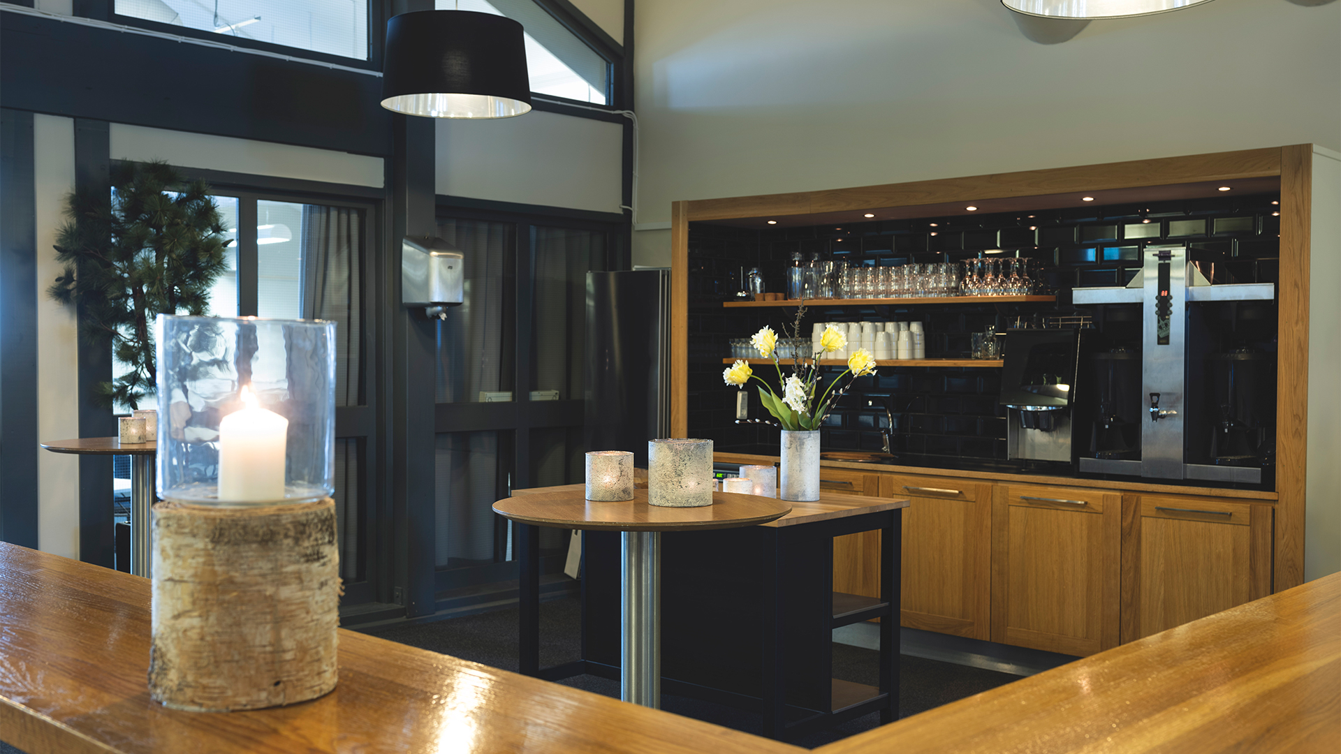 Modernt caféinteriör med träbord och inredning, tända ljus och blombukett, elegant och mysig atmosfär