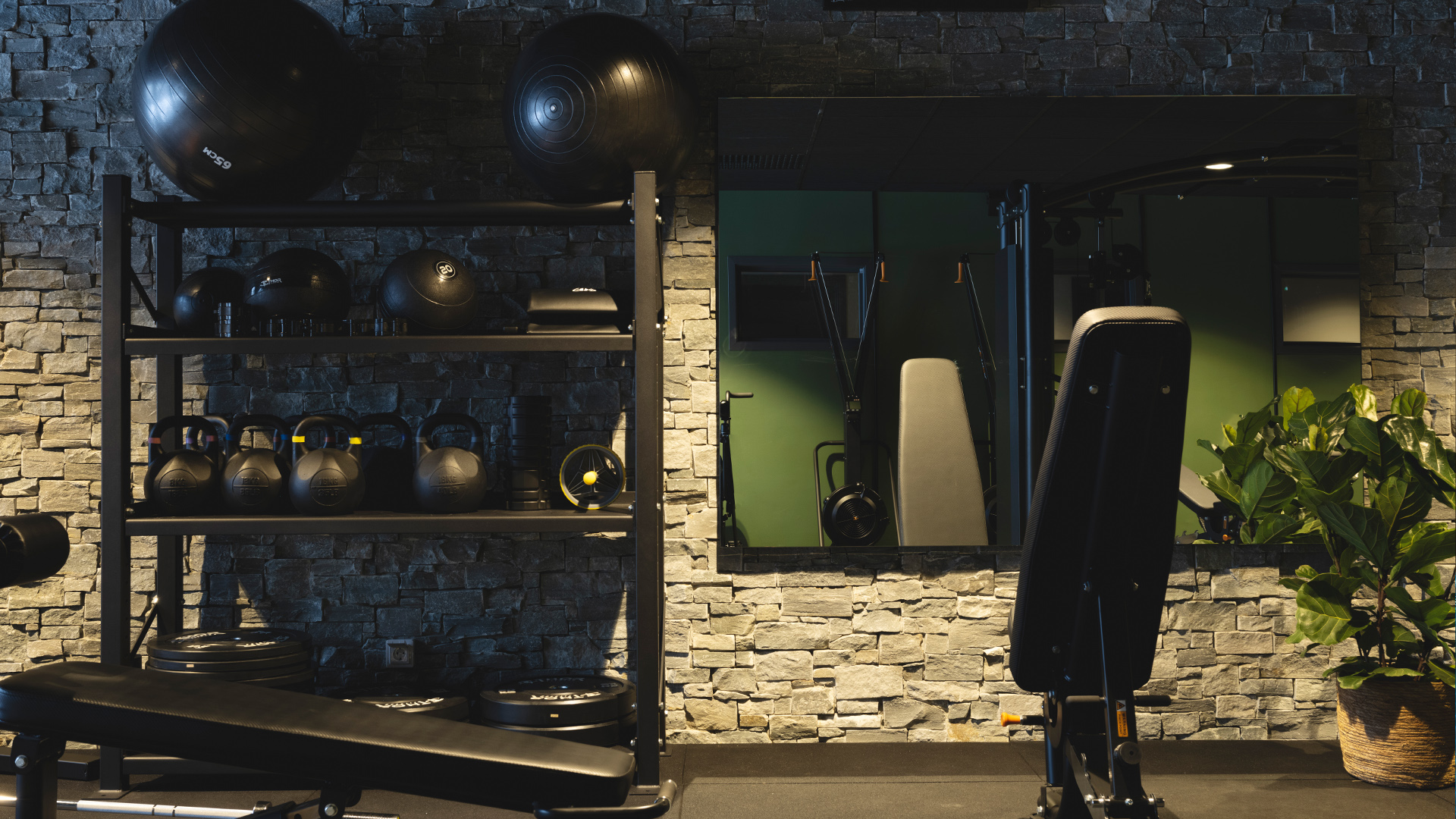Gym med kettlebells, träningsbänk och spegelvägg, moderna träningsredskap och stenvägg