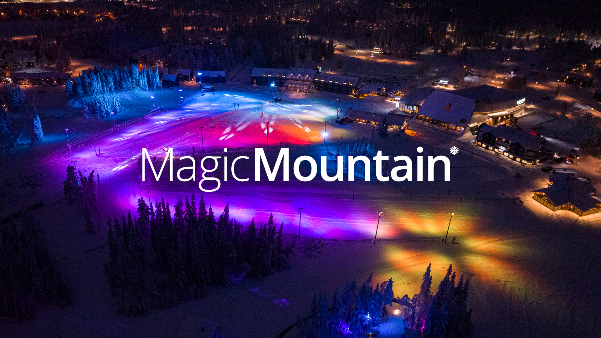 Nattvy över Magic Mountain med färgglada ljus på snön och omgivande byggnader