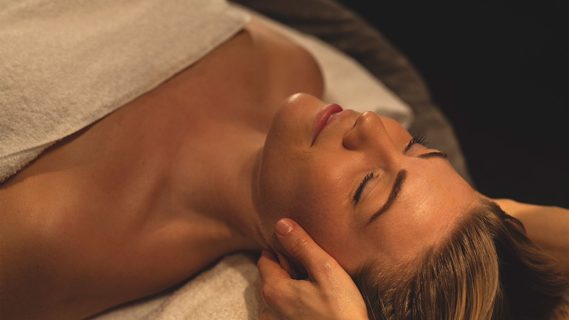 Kvinna som njuter av avkopplande massage, liggande under en handduk