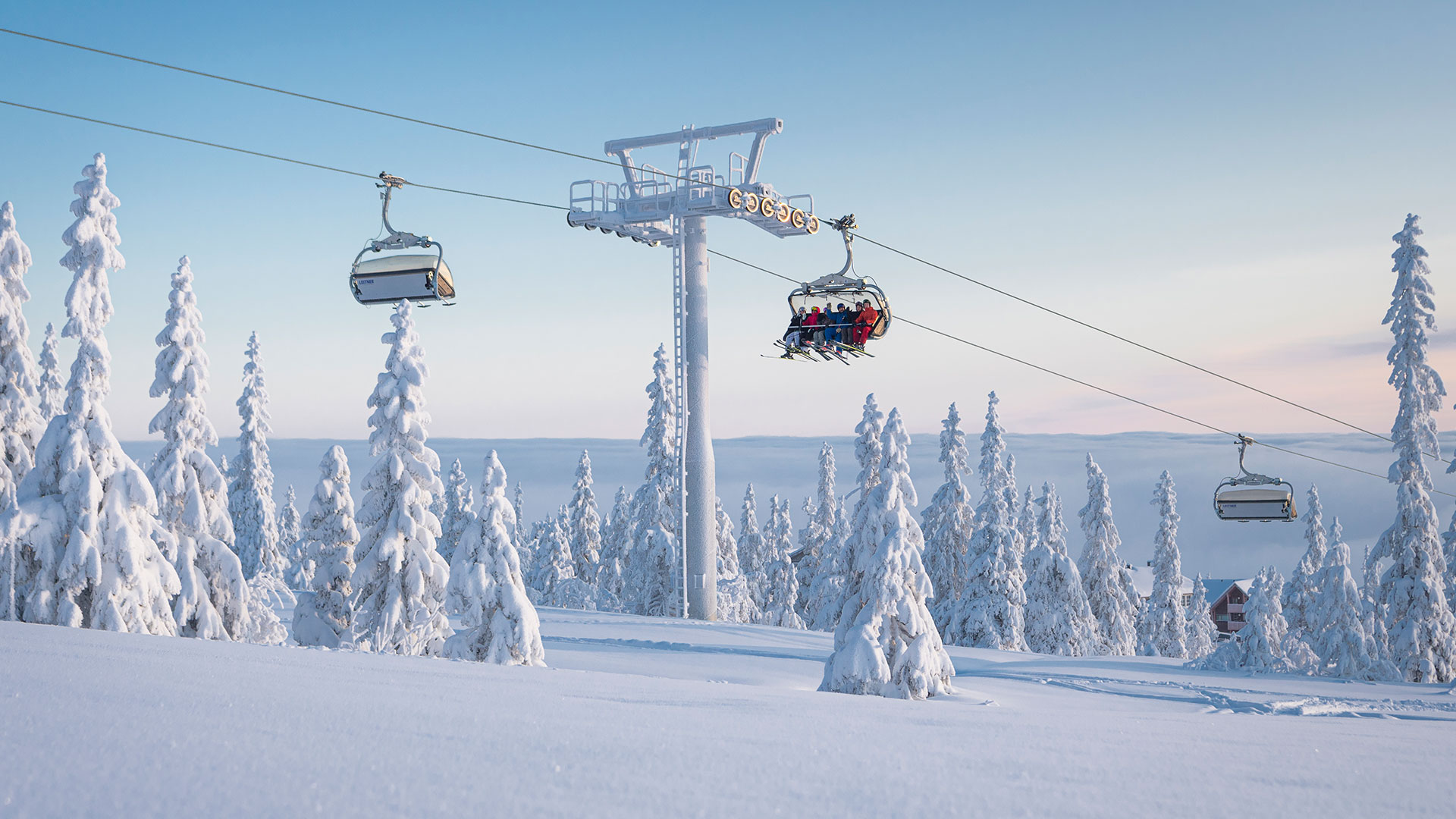 Ski lift in a snow-covered mountain landscape with snow-covered trees and a blue sky