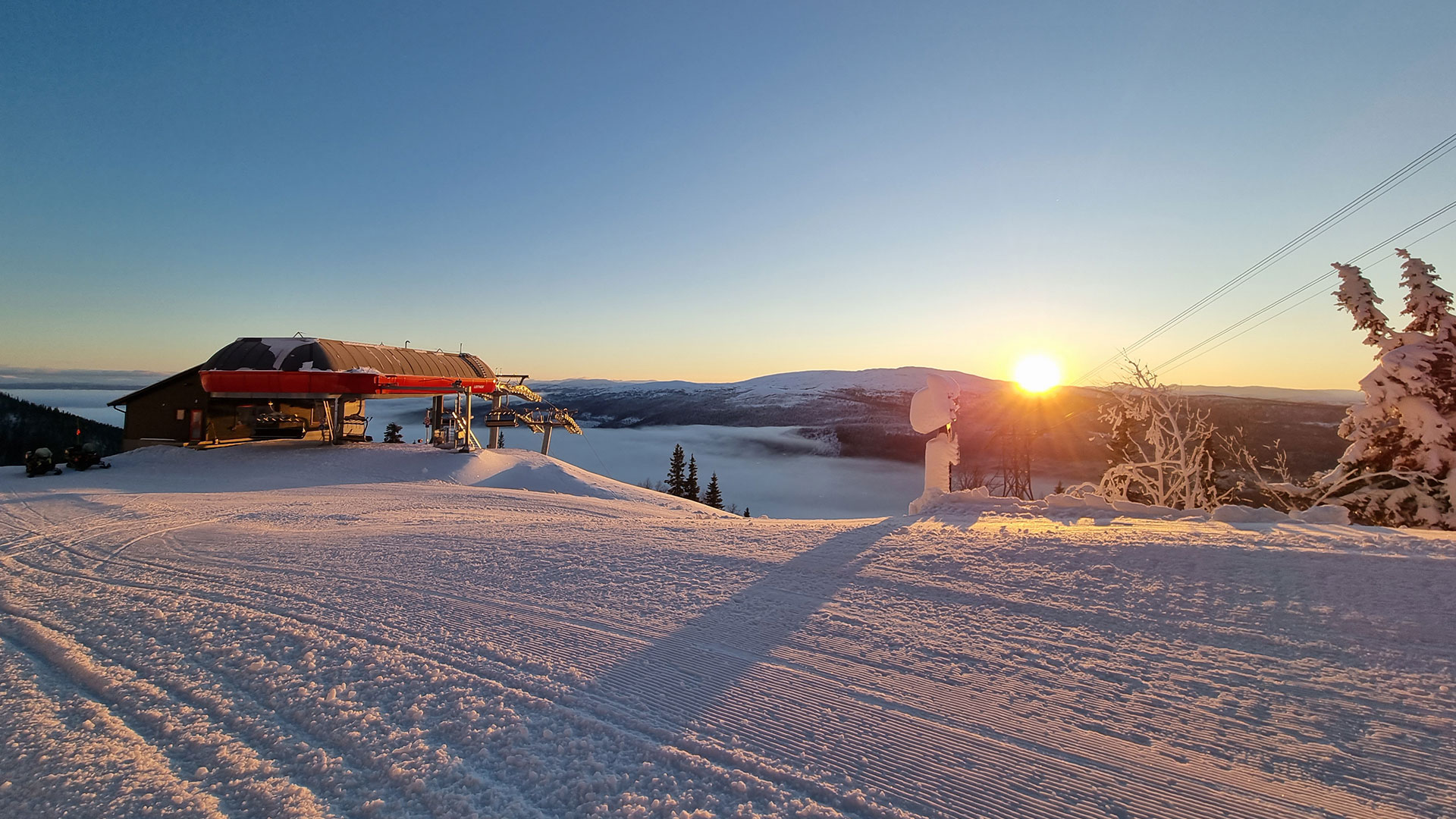 Soluppgång över snöig skidbacke i Åre, Sverige, med sittlift och vinterlandskap i bakgrunden