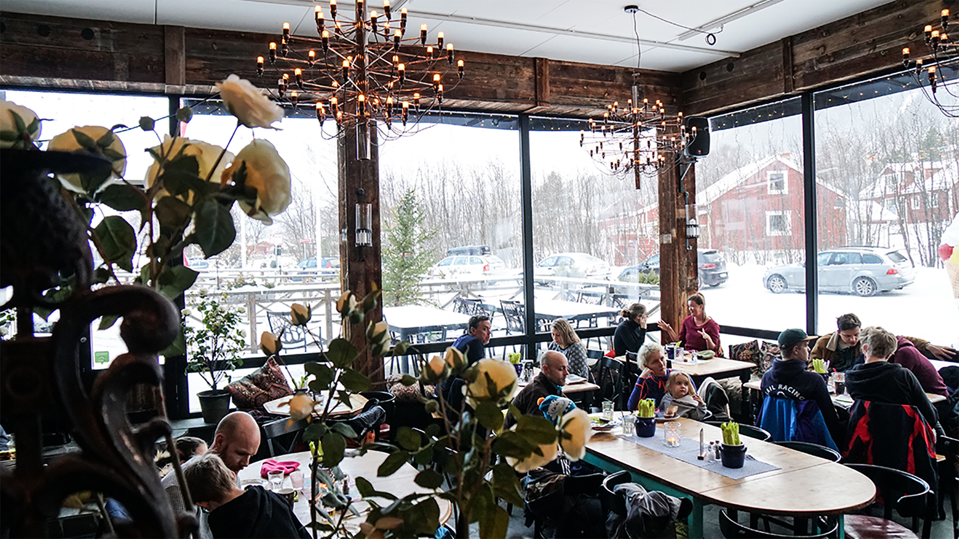 Fullsatt restaurang med vinterutsikt i Sverige, med gäster som njuter av måltider vid fönsterborden