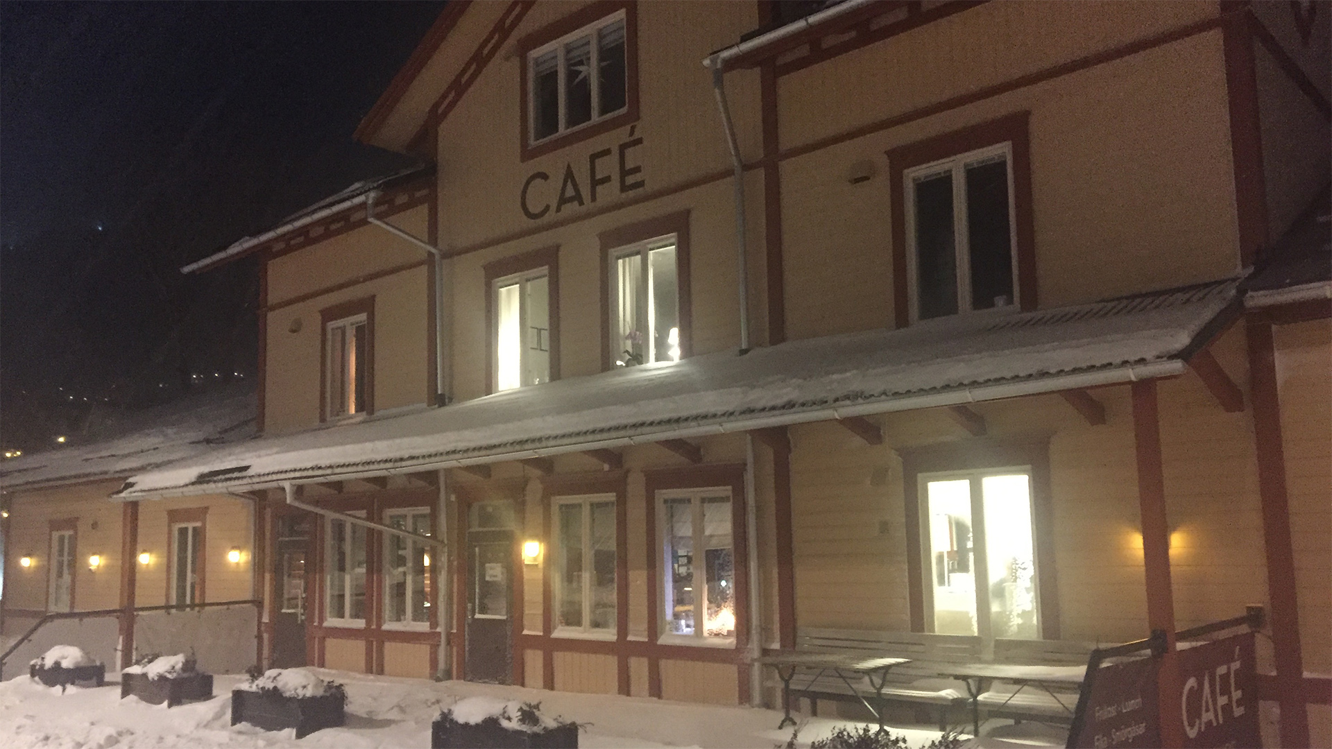 Café vid kvällen, beläget i en snöig miljö med upplyst entré och traditionell arkitektur