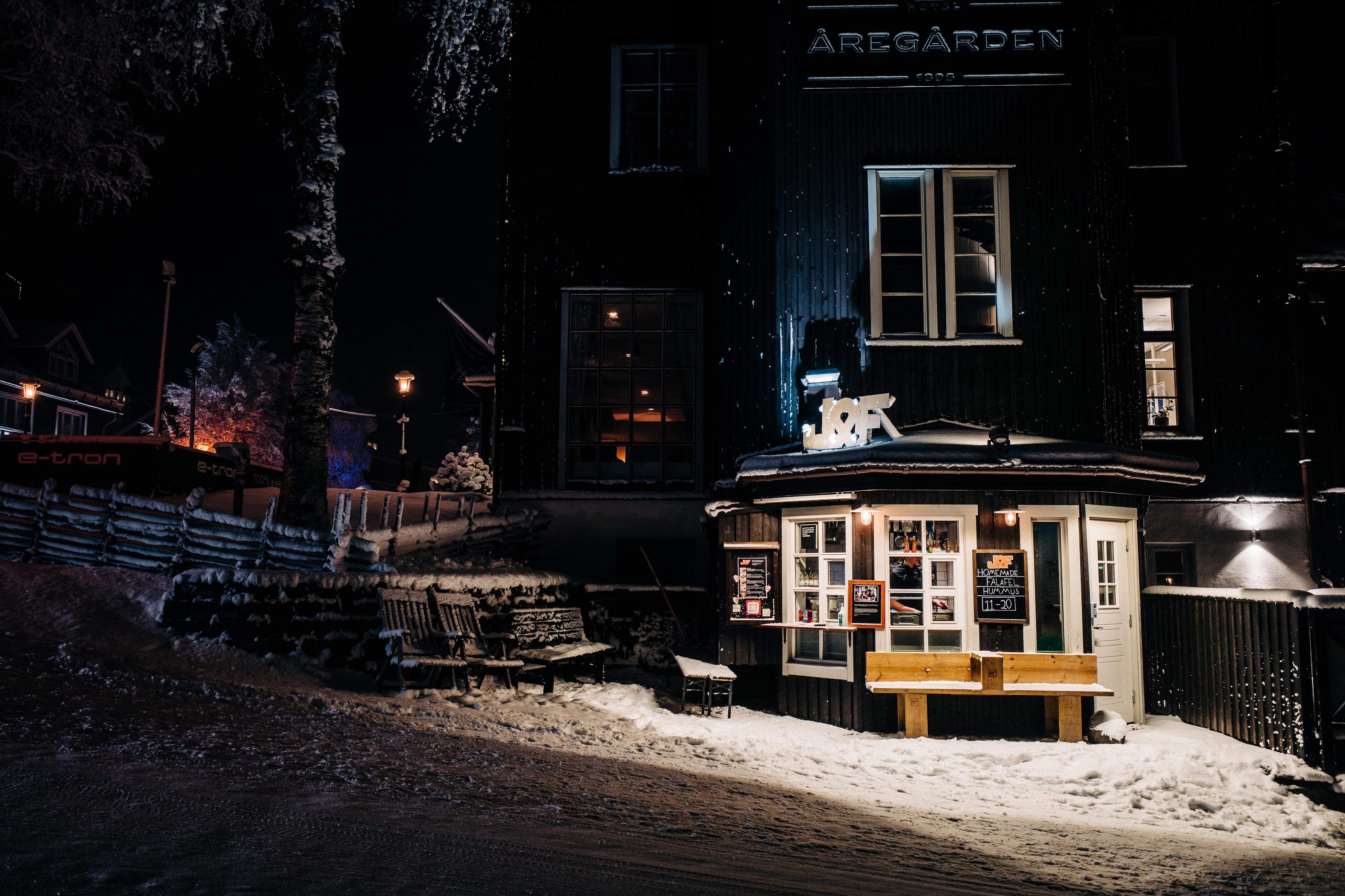 Schneebedecktes Nachtbild von Åregården im Zentrum von Åre, mit beleuchtetem Eingang und Winterdekorationen