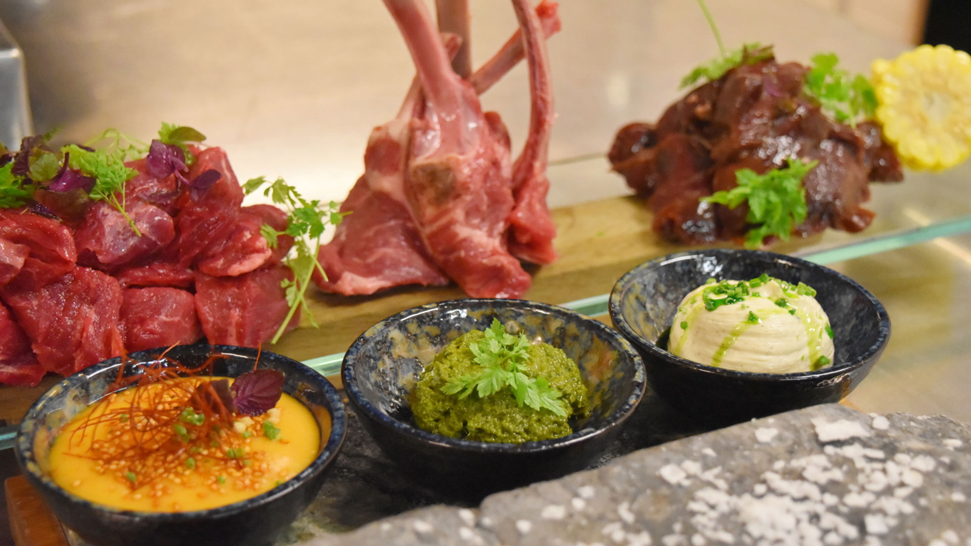 Assortiment av färskt kött med garnityr, serverat med tre olika såser i skålar: krämig, örtbaserad och kryddig dressing