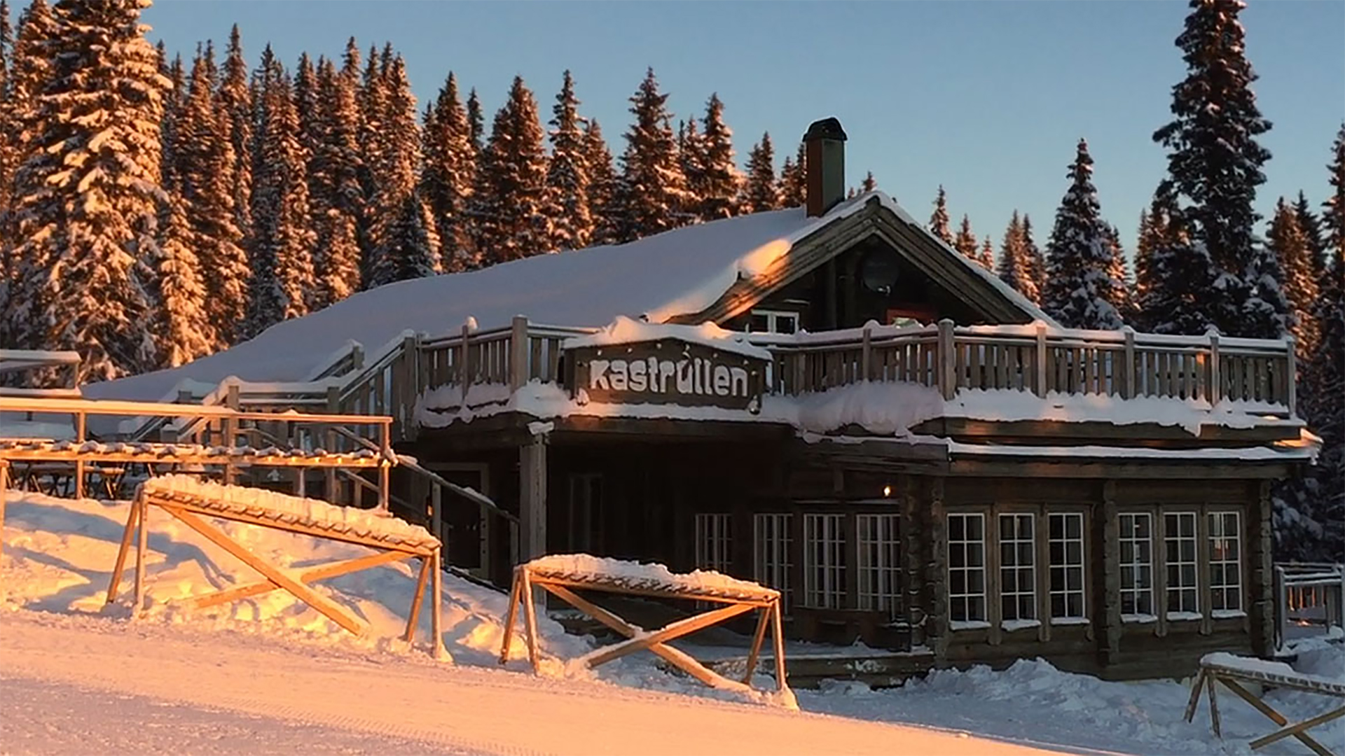 Fjällstuga i solnedgång med snötäckta tak och träd, Åre, Sverige