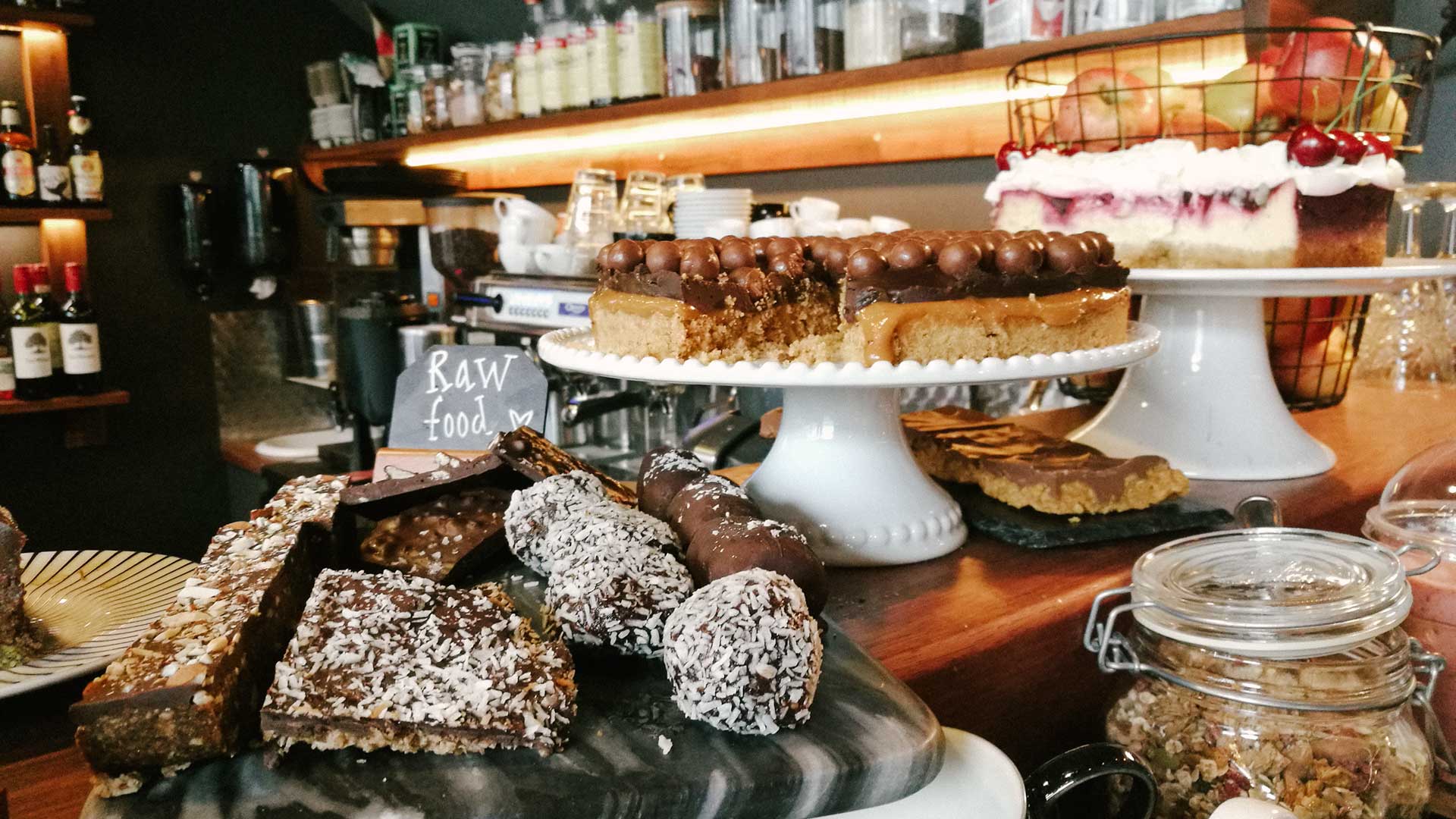 Cafédisken med ett urval av desserter inklusive raw food-kakor, chokladtårta och bärcheesecake på ställ