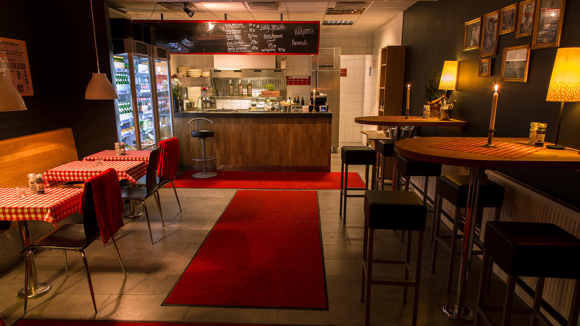 Gemütliches Café-Interieur mit roter Einrichtung, karierten Tischdecken und Kerzen auf den Tischen, was eine intime und einladende Atmosphäre schafft