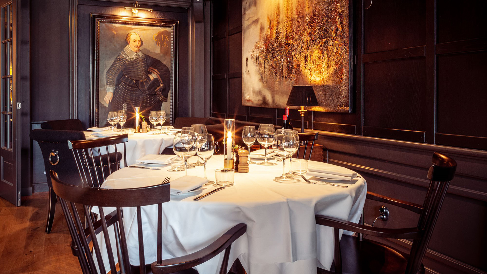Elegant restauranginteriör med stilfullt dukade bord, omgiven av konstverk och dämpad belysning