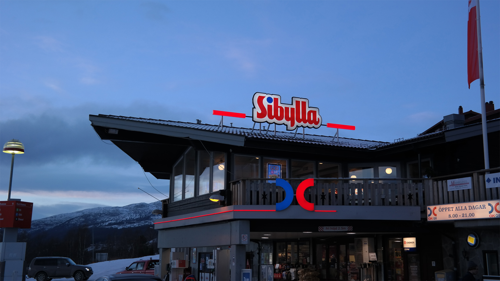 Sibylla-restaurang på fjällstation med snötäckta berg i bakgrunden under skymning