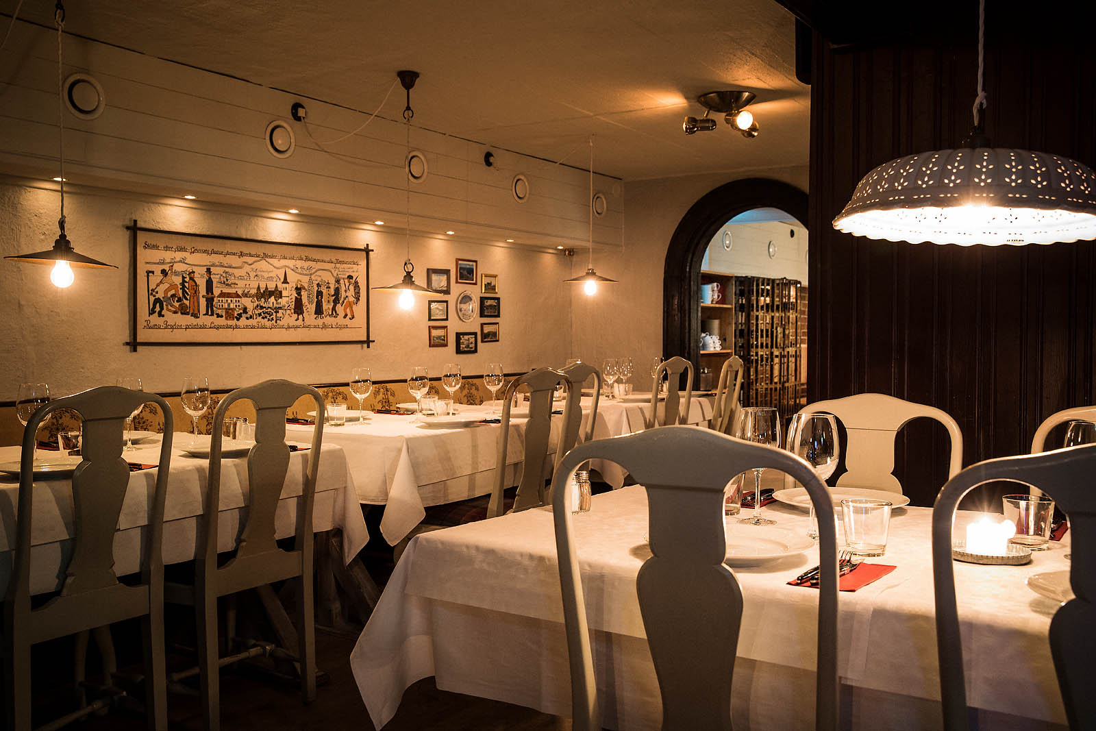 Restaurang med klassisk inredning, inklusive dukade bord med vita dukar, eleganta stolar och stämningsfull belysning