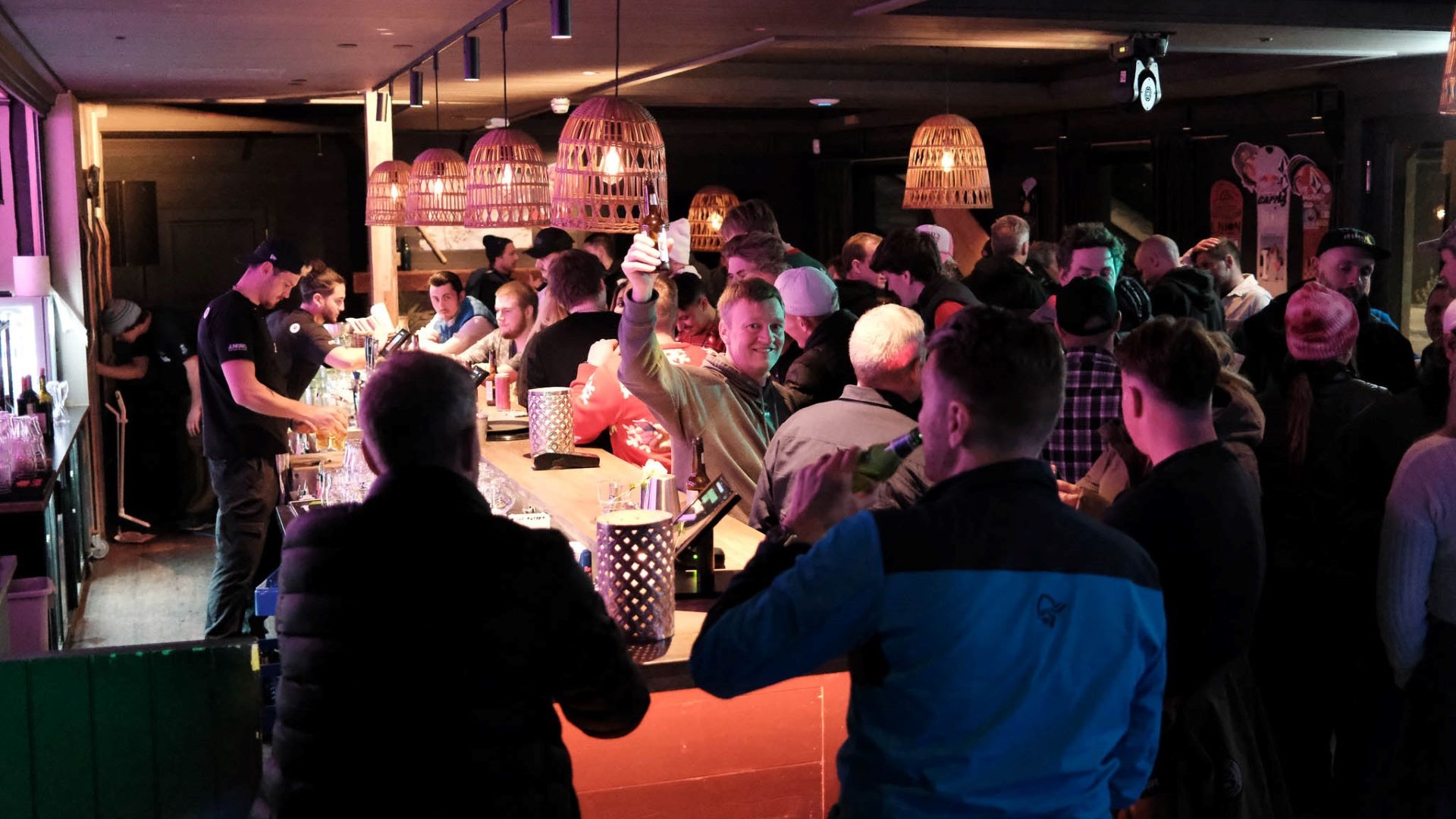 Människor samlade vid en livlig bar på kvällen, upplyst av mjuka lampor