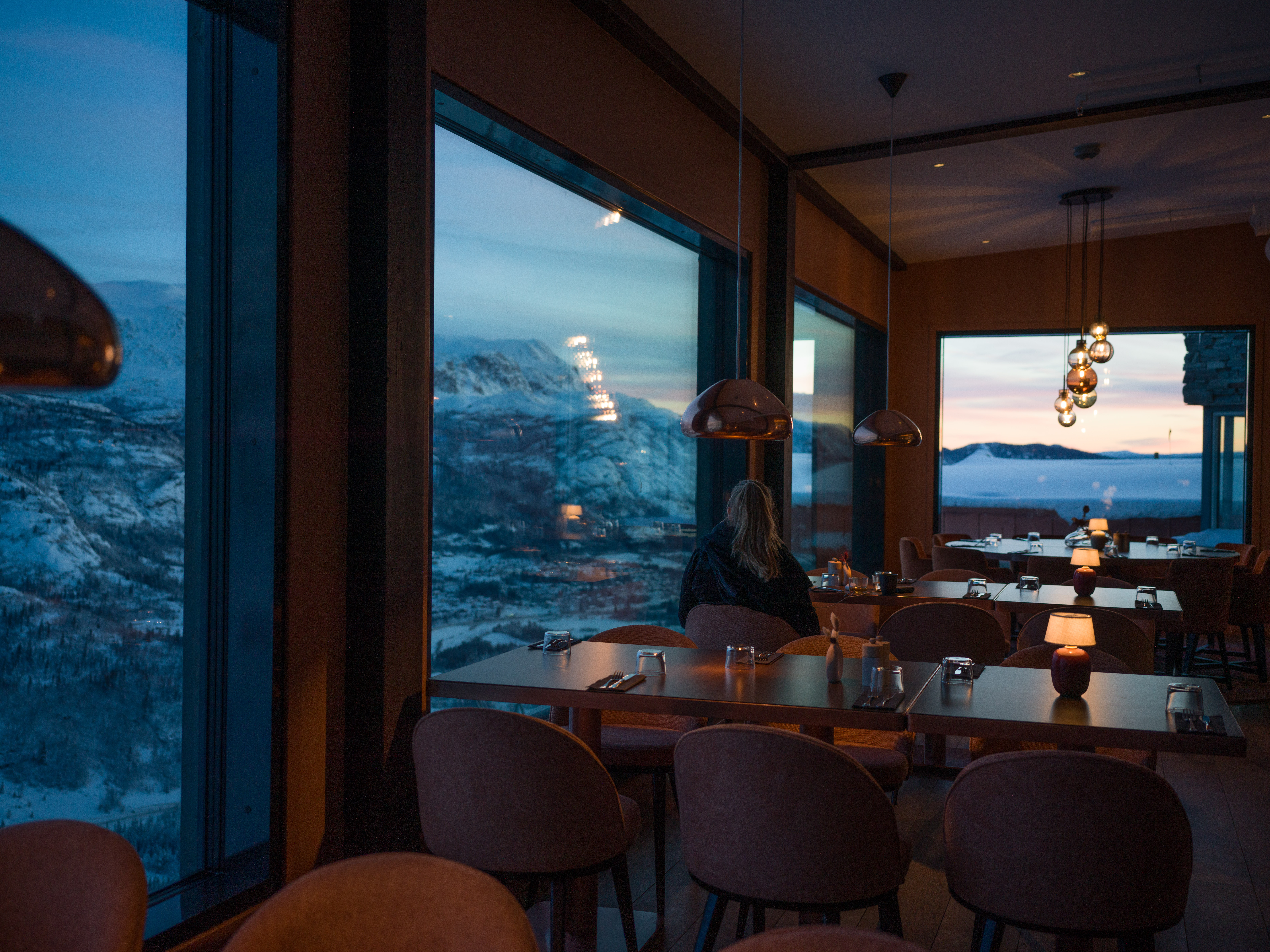 Restaurang med panoramautsikt över snöklädda berg och solnedgång. Mysig atmosfär med tända ljus