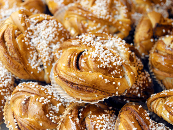 Kanelbullar med pärlsocker, en populär svensk fika, ligger nygräddade på ett bakplåtspapper