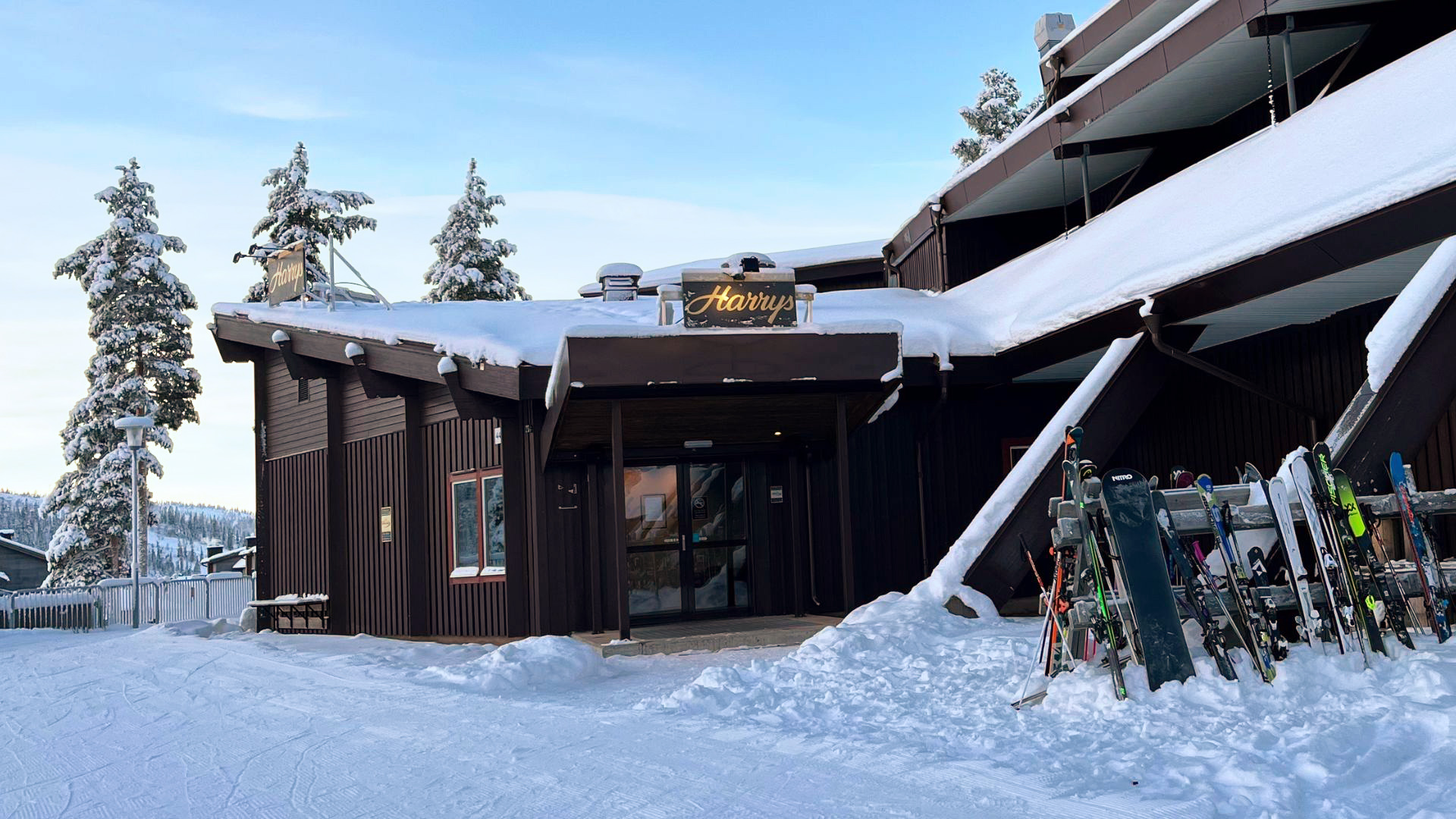 Snötäckta tak och skidor utanför en träbyggnad på skidort i fjällen, Sverige