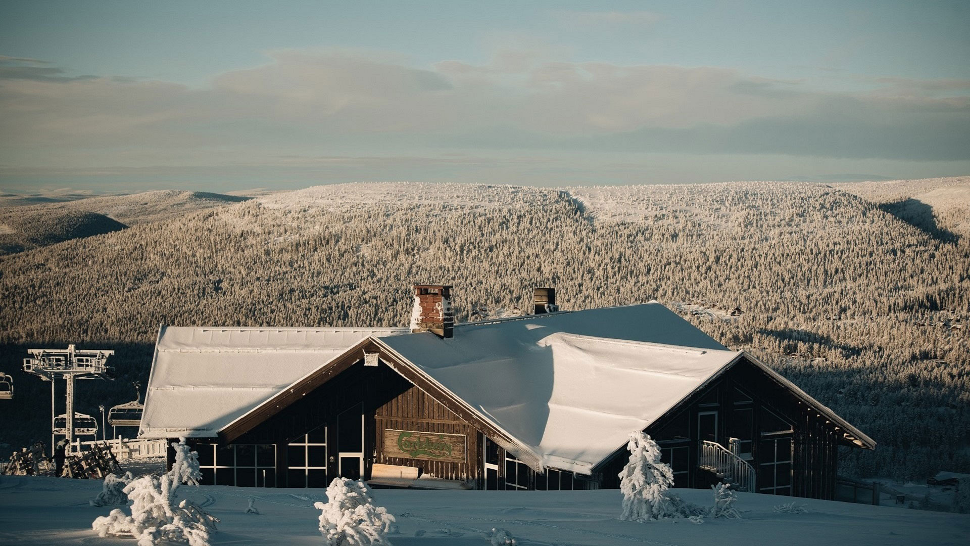 Snötäckt fjällstuga med utsikt över snöklädda fjäll och skidliftar i Sverige