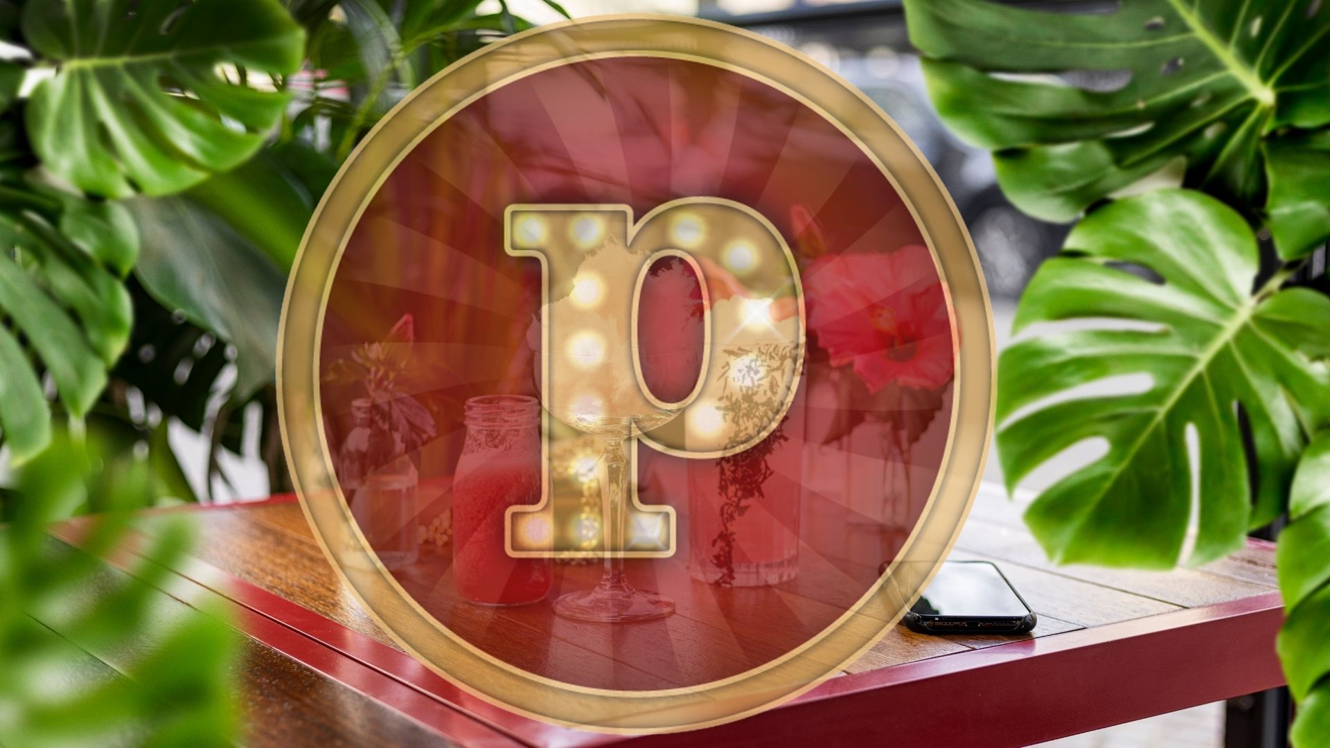 Rund guldmedaljong med bokstaven "P" i centrum, omgiven av gröna växter och ett träbord i bakgrunden