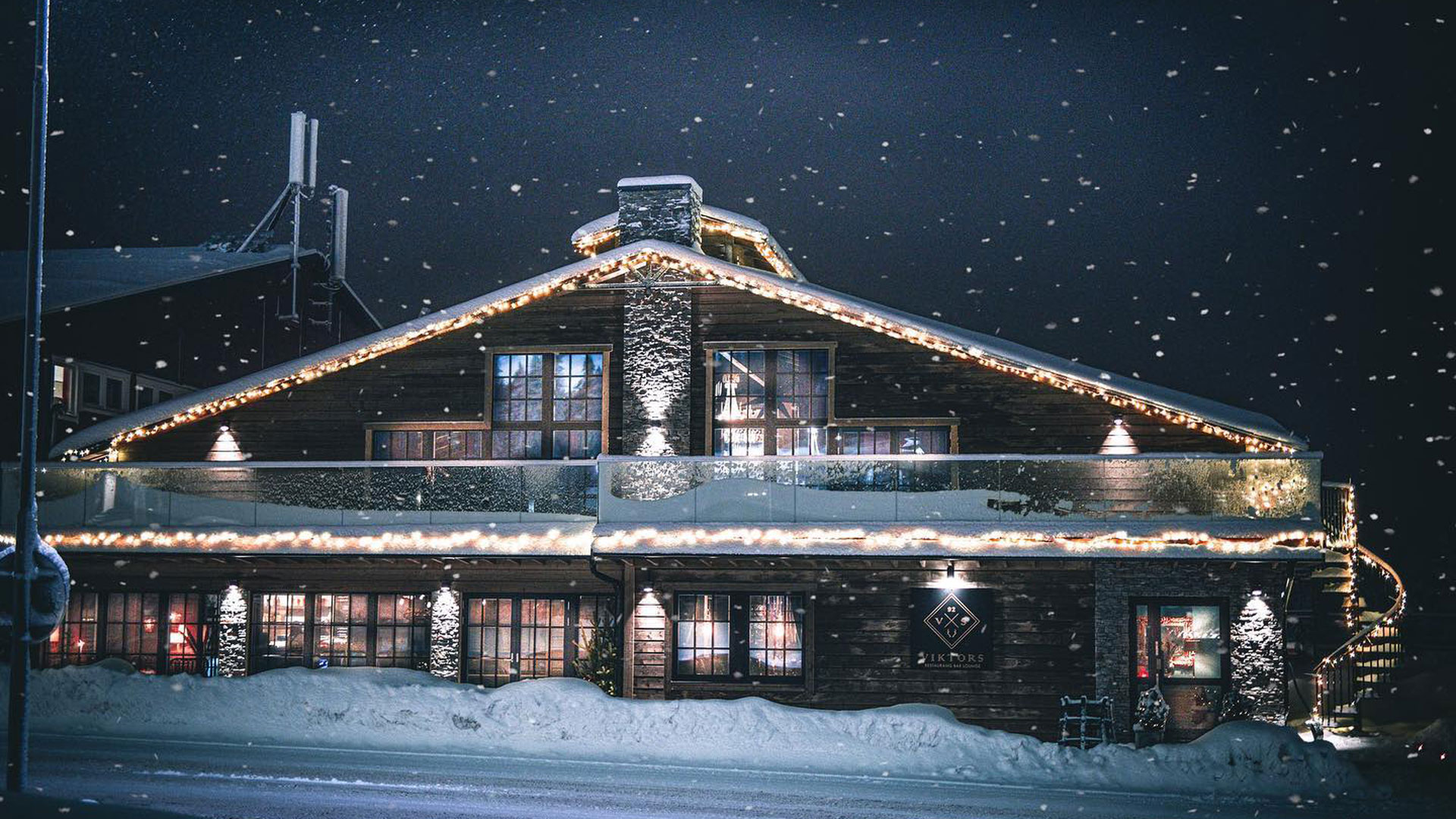 Snötäckt timmerstuga med julbelysning en vinternatt