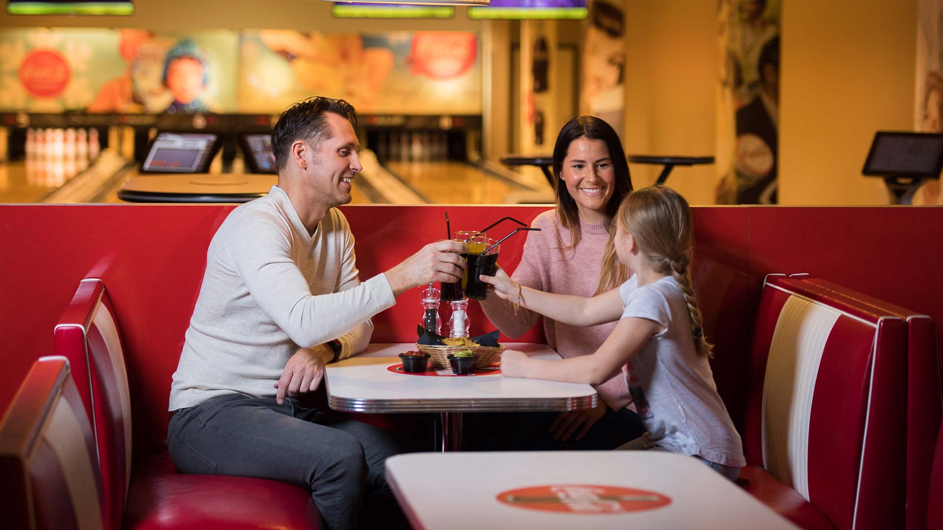 Familj skålar med drycker i bowlinghallens café