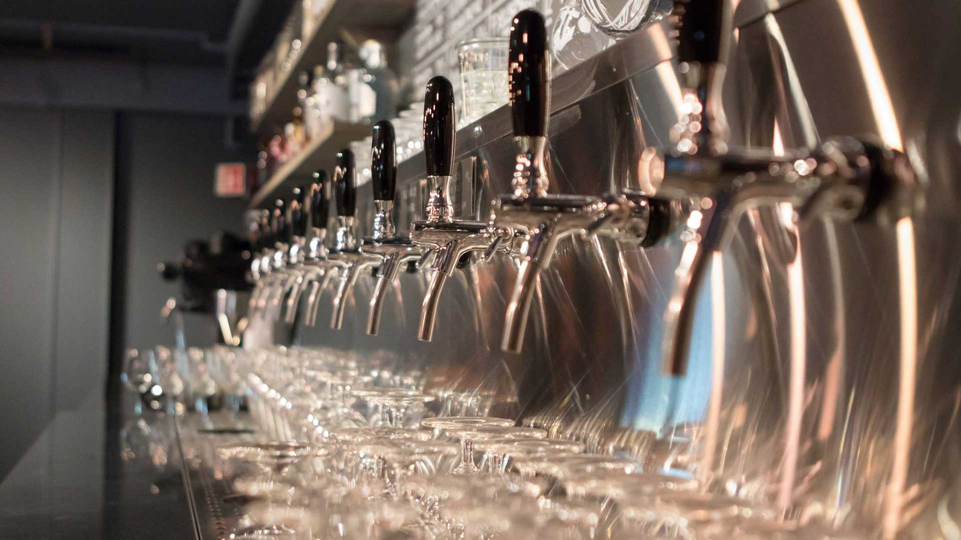 Ölkranar i en modern bar med spegelblank yta och glas redo för servering