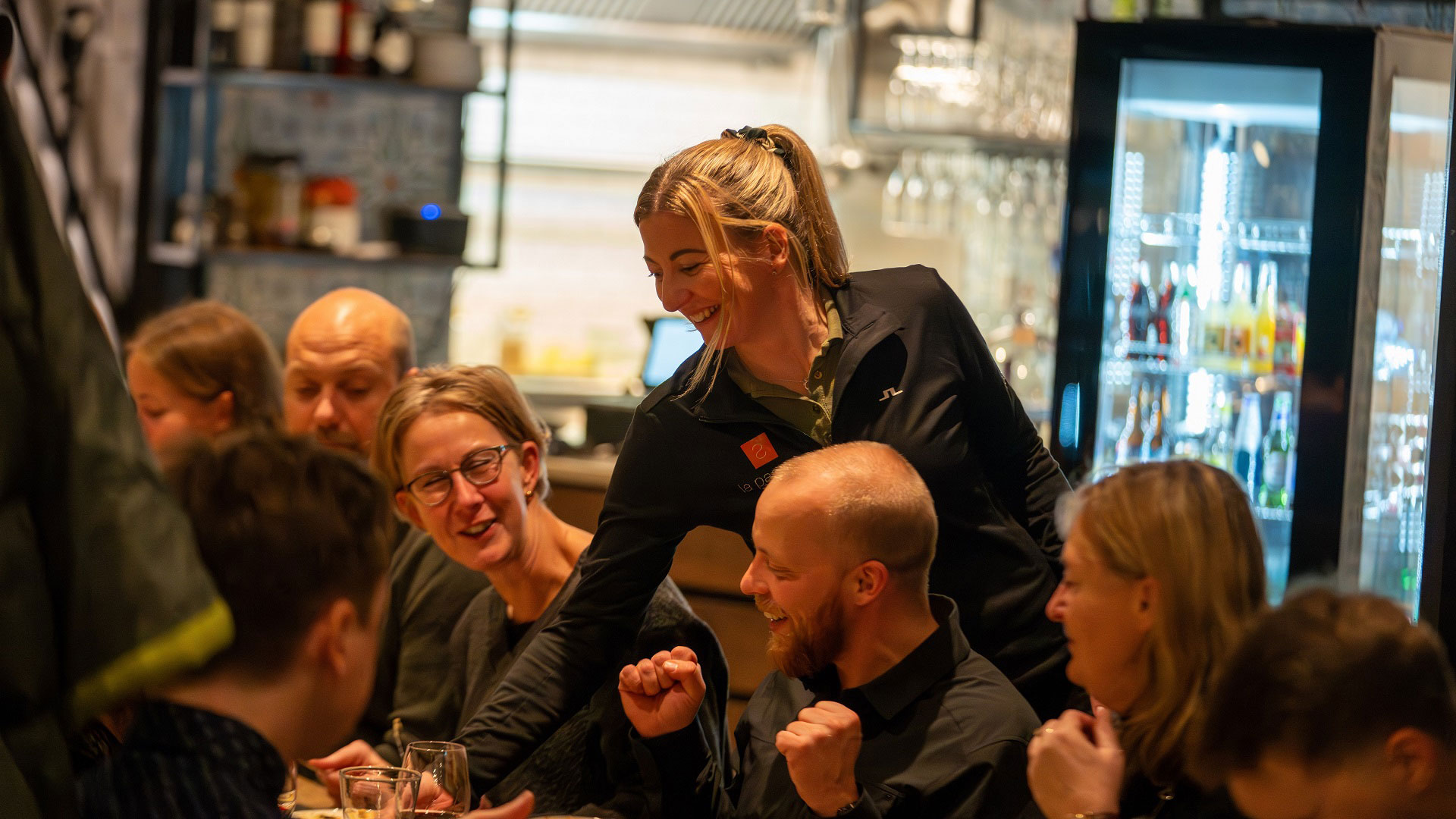 Serverar på restaurang med glada gäster i samtal, inredning i bakgrunden
