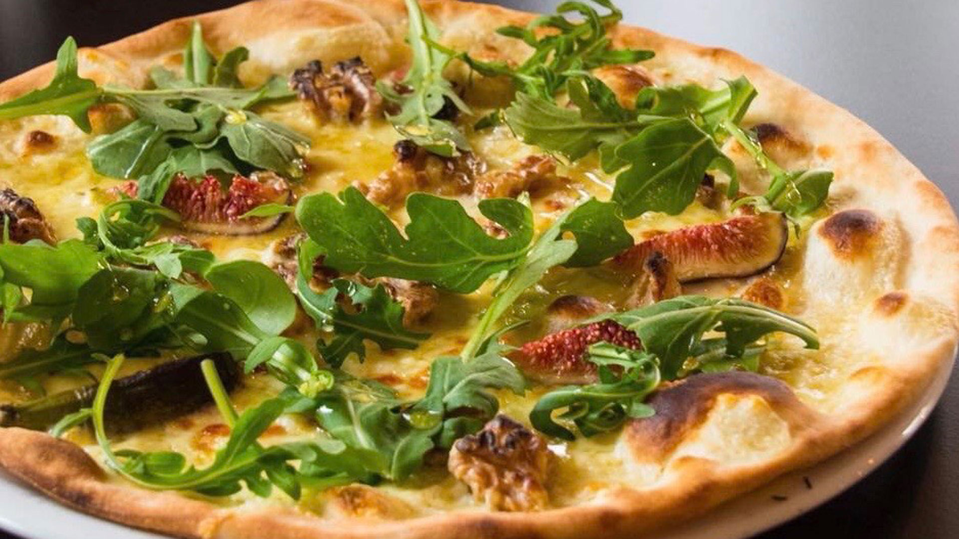 Pizza med fikon, valnötter och ruccola på tunn, gyllenbrun botten