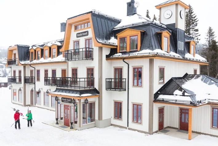 Historiskt hotell i snötäckt bergsmiljö med två skidåkare utanför