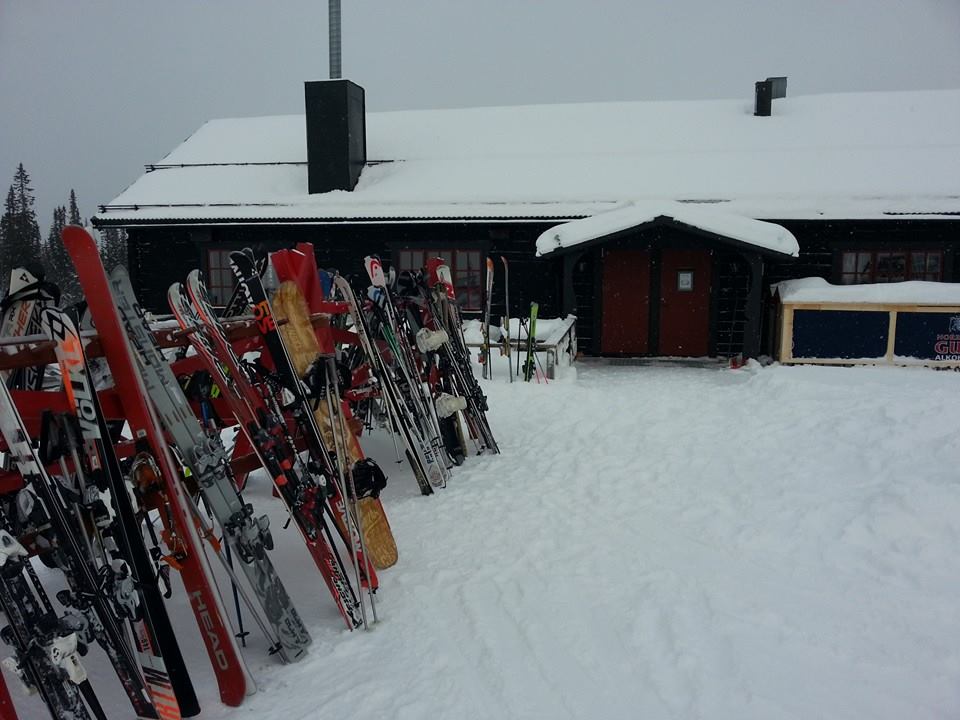 Skidor placerade utanför en snötäckt stuga i fjällen, vintertid