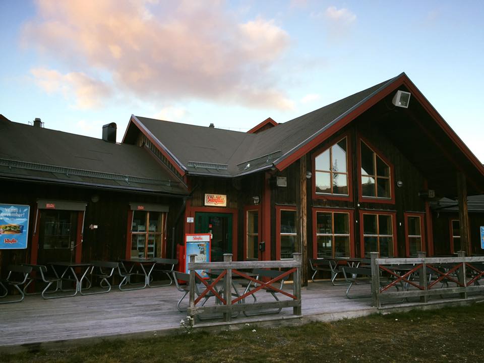 Trästuga med uteplats och molnig himmel i bakgrunden