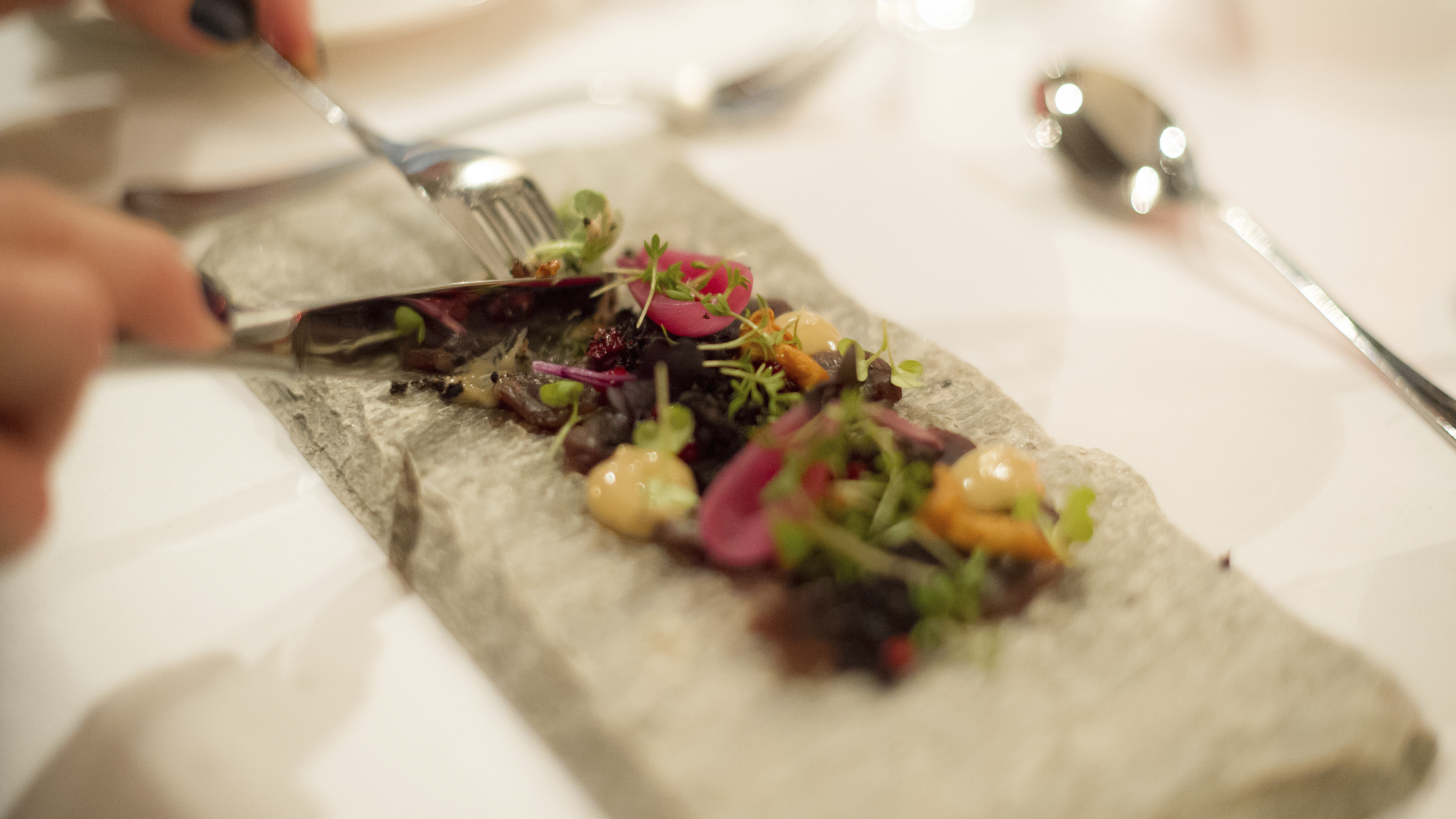 Fine dining med elegant upplagd gourmeträtt, garnerad med örter och såser på en stenplatta