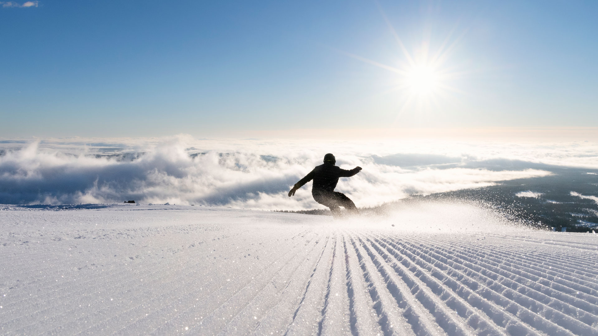 Snowboardsentusiast utför carving på solig skidbacke med vy över molntäckt landskap