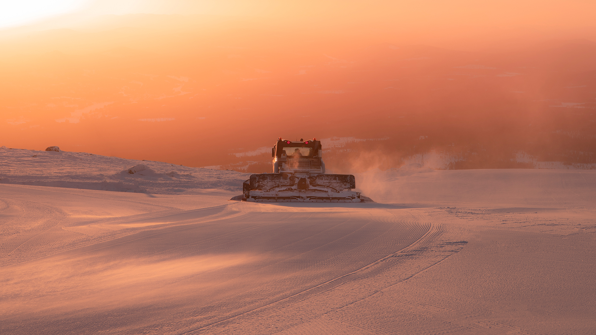 Snowplow at sunset in a mountainous landscape