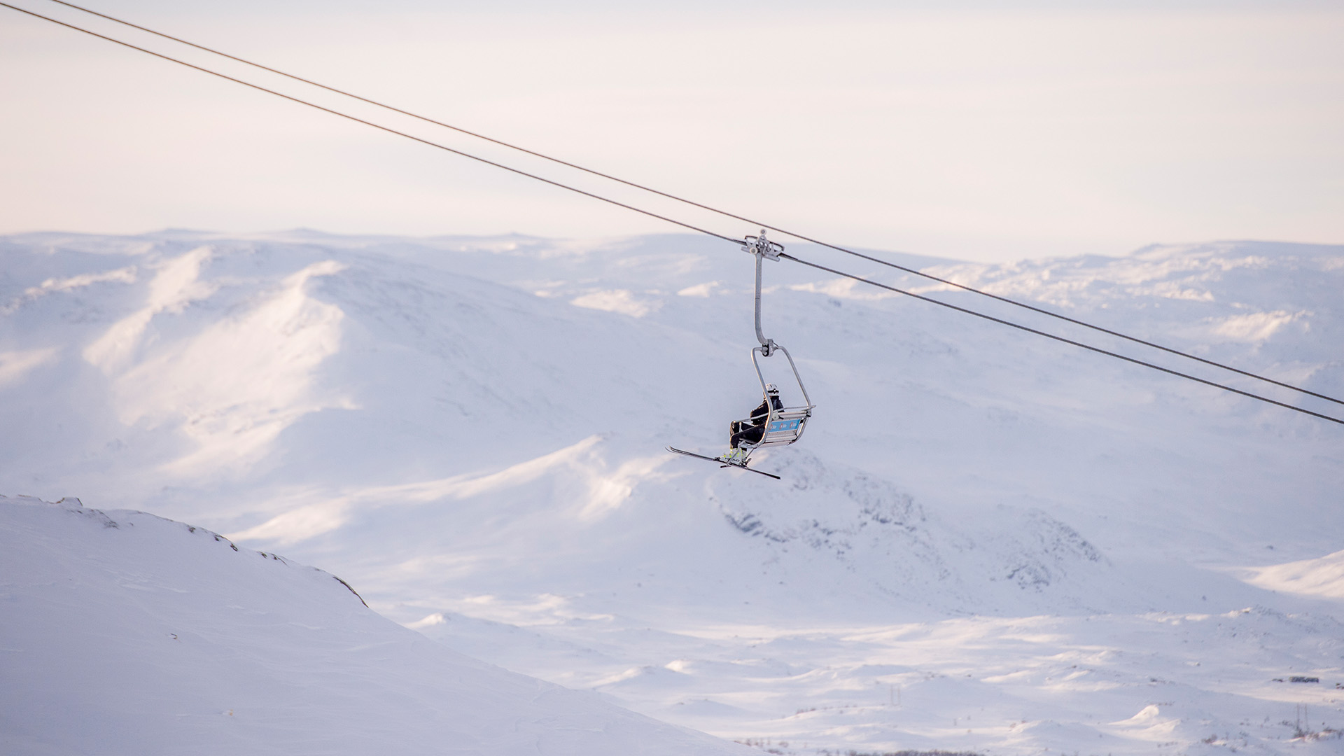 Skidlyft över snötäckt bergslandskap i fjällen under klar himmel