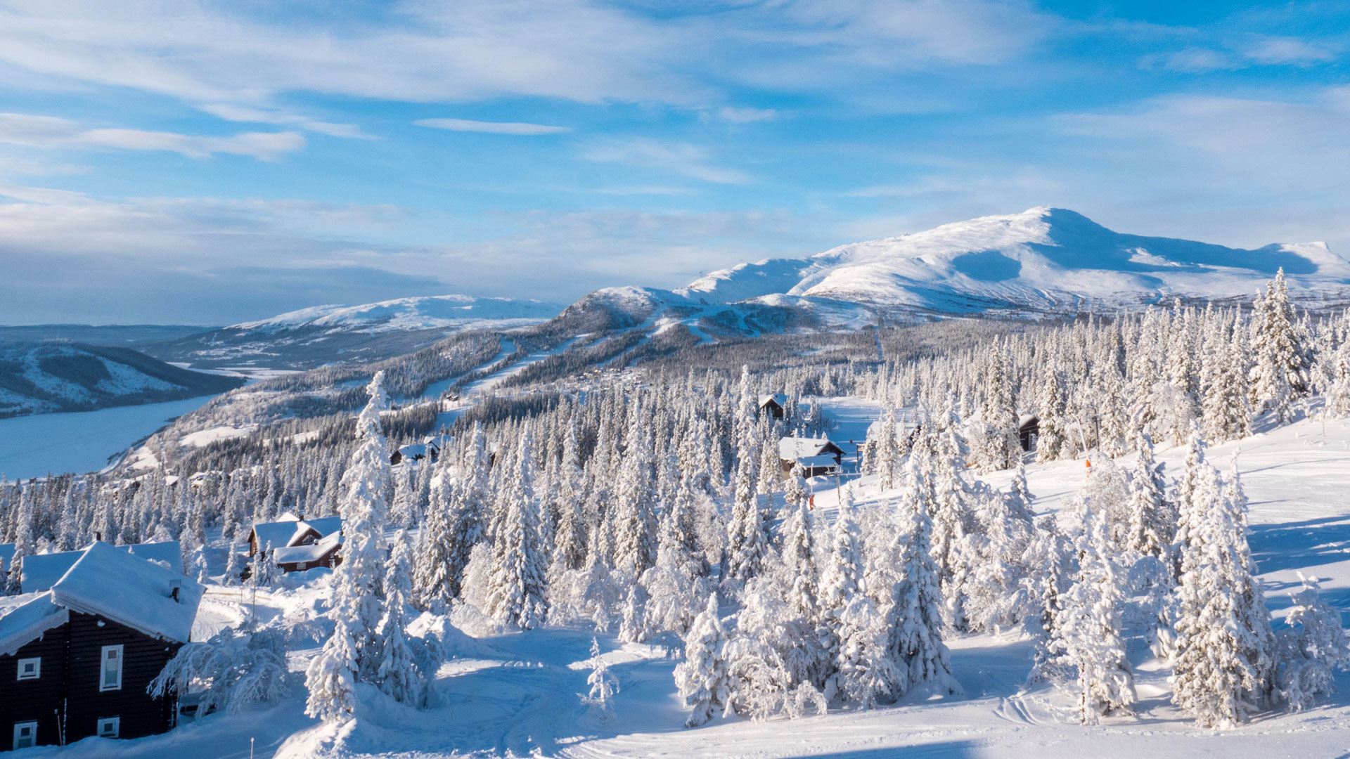 Snedækket fjellandskab i Åre, Sverige, med vinterskov og fjeldhytter under en klarblå himmel