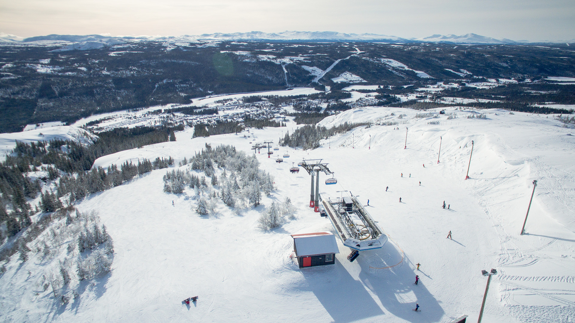 Svensk skidort med snötäckta berg och skidåkare som använder en skidlift under en klar vinterdag