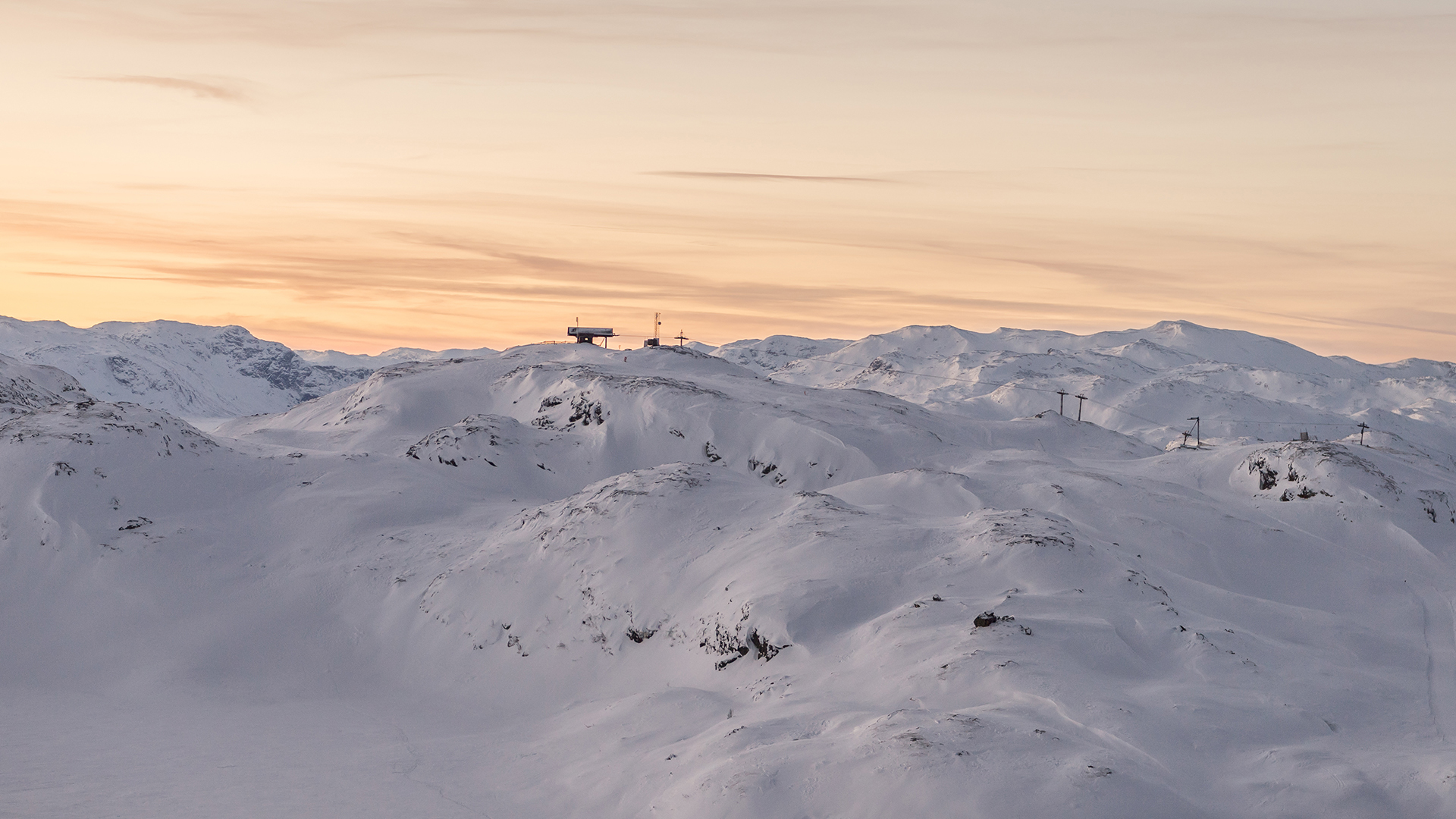 Snötäckt bergslandskap vid solnedgång med skidlift i bakgrunden, Skandinavien