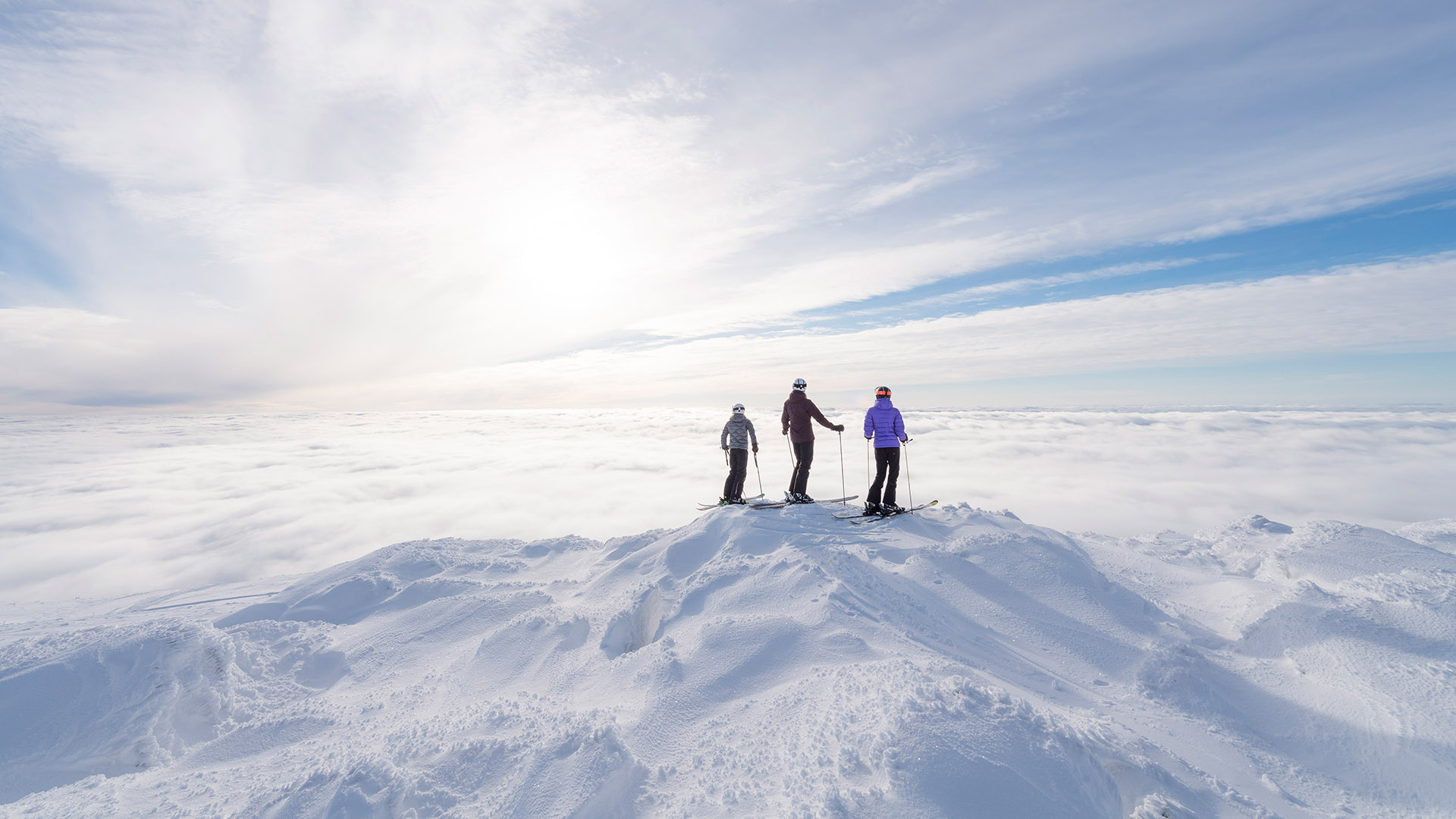 Skidåkare på snötäckt fjälltopp under klar himmel