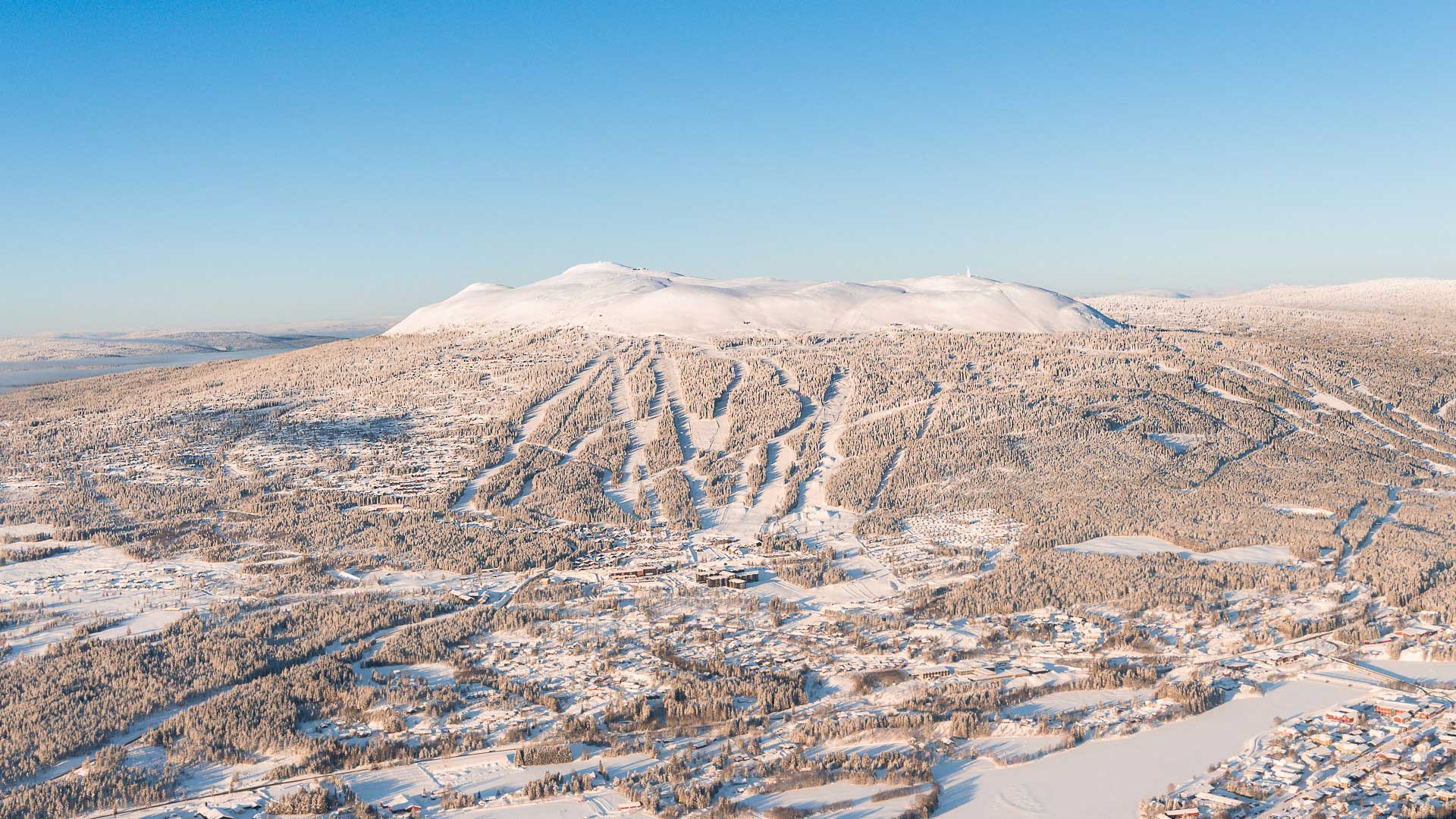 Vinterlandskap med snötäckta fjäll och skidbackar i Trysil, Norge under klarblå himmel. Perfekt destination för skidåkning och vinterturism