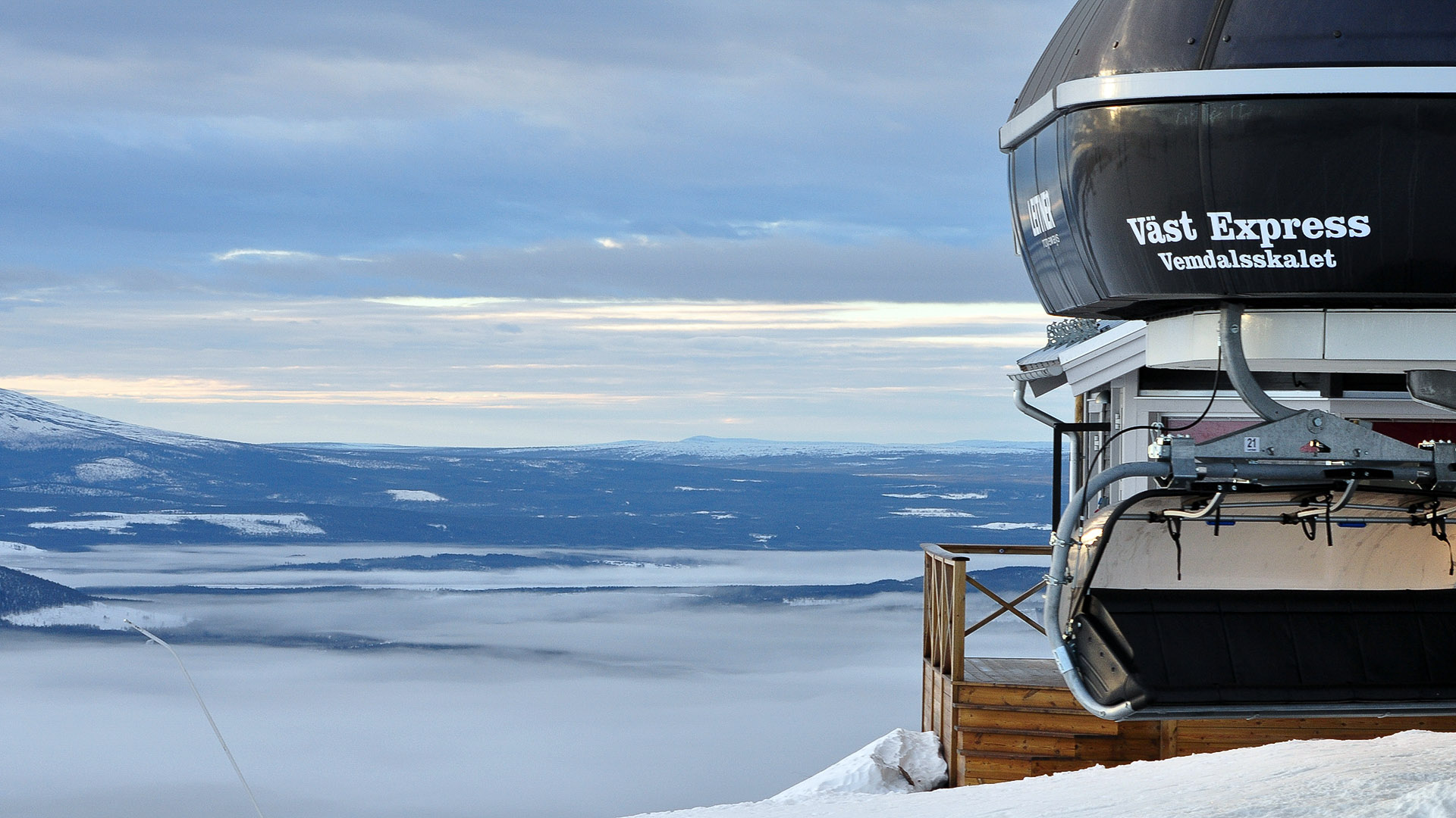Skidlift Väst Express på Vemdalskalet med snötäckta berg och molntäckt dal i bakgrunden