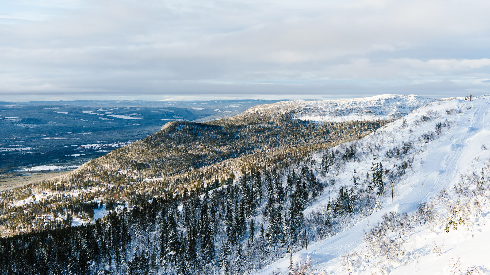 Winter landscape with snow-covered mountains and forests in Sweden under a cloudy sky